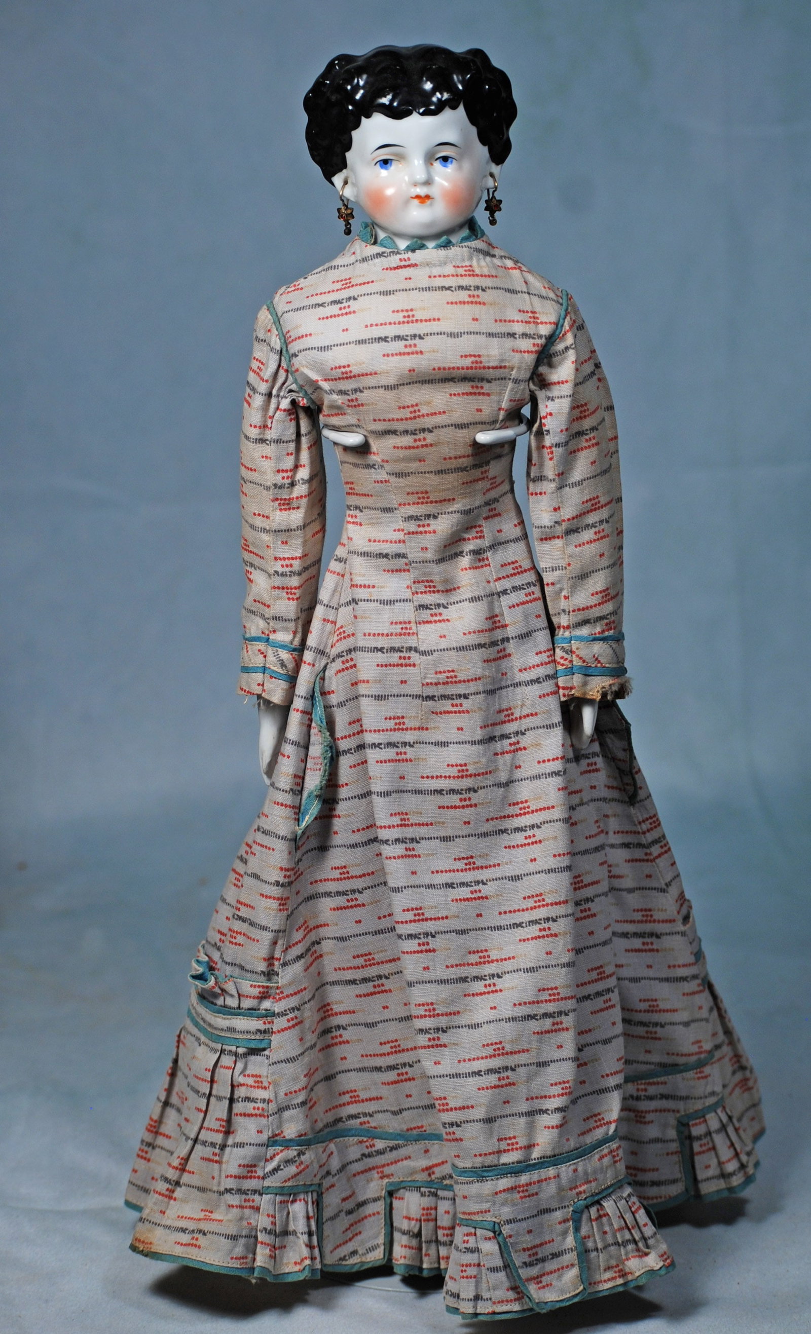 GERMAN PORCELAIN LADY WITH PIERCED EARS: 16”. Porcelain shoulderhead with sculpted black hair in deep waves and curls, center-parted and waved behind partially modeled pierced ears, painted features, blue eyes, red and black eyeliner, 