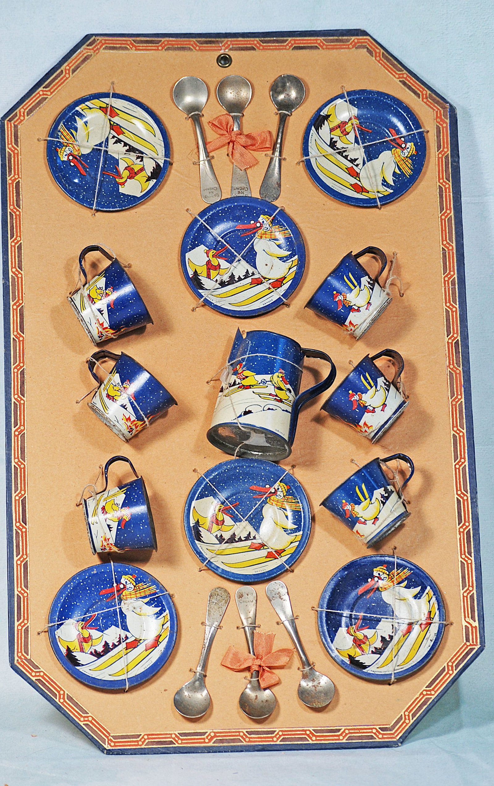 TIN LITHOGRAPHED “MOTHER GOOSE” TEA SET: 17” x 11” heavy cardboard panel displays a tin lithographed toy tea set featuring various illustrations of Mother Goose adventures; six place set with cups, saucers, plates, pitcher and sp