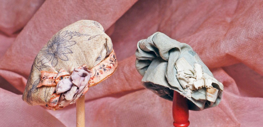 TWO ANTIQUE HATS FOR SMALL DOLLS. (1) Cotton print: TWO ANTIQUE HATS FOR SMALL DOLLS. (1) Cotton print flat top bonnet gathered onto padded pink print band, accented with flower and bows, dark gray cotton lining, fits approximately 7”-7 ½” head ci