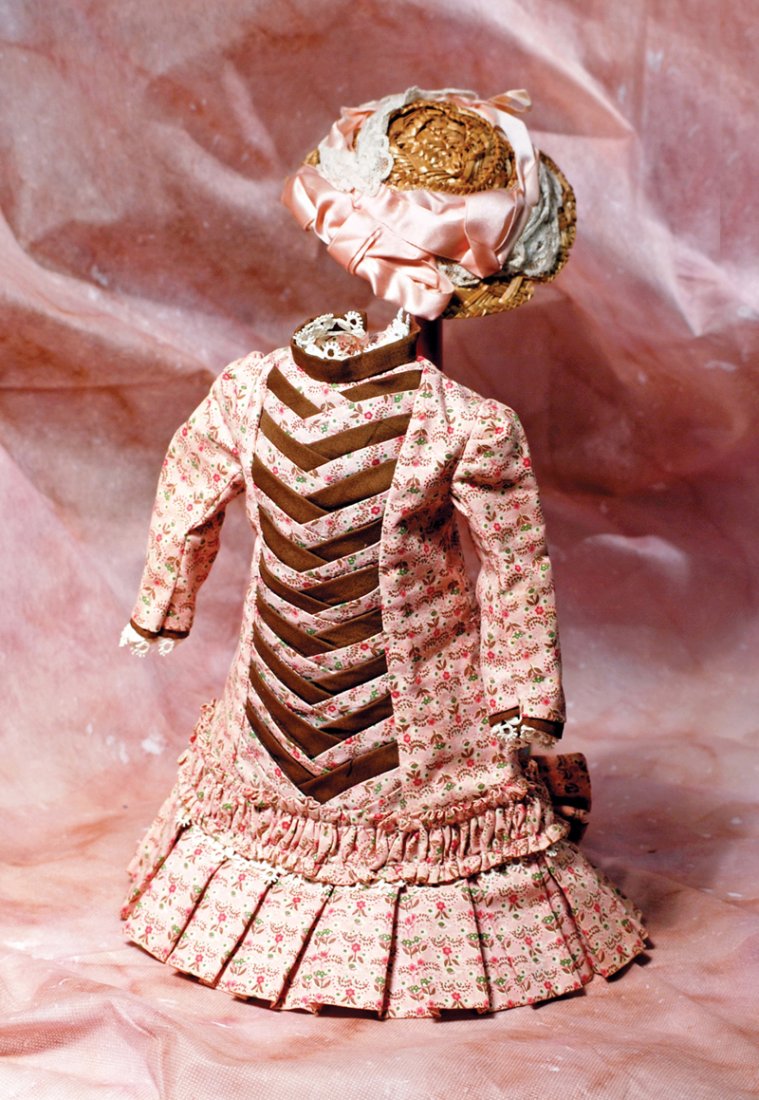 COTTON DOLL DRESS & STRAW BONNET. 4 ½” shoulder width,: COTTON DOLL DRESS & STRAW BONNET. 4 ½” shoulder width, 11” length. Princess style dress of pink cotton print has inset front panel with folded and inter-laced bands of brown fabric and print fabr