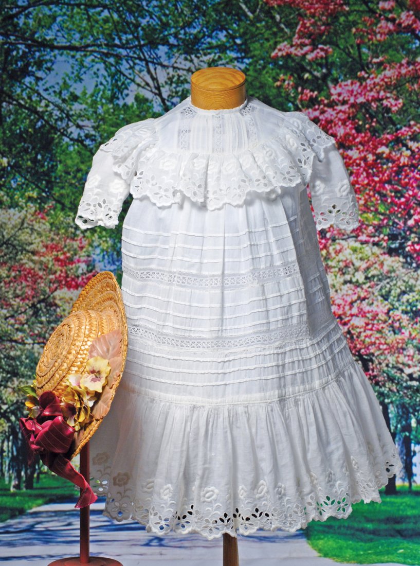 WHITE COTTON DRESS WITH CUTWORK TRIM AND STRAW BONNET.: WHITE COTTON DRESS WITH CUTWORK TRIM AND STRAW BONNET. Fine white cotton dress features a rounded yoke with lace and tucks, cutwork ruffle and sleeves, gathered skirt with horizontal stitched tucks an