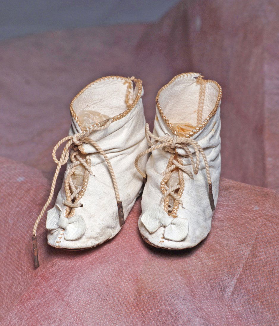 PAIR OF ANTIQUE LEATHER DOLL BOOTS. 2 ½” L. White: PAIR OF ANTIQUE LEATHER DOLL BOOTS. 2 ½” L. White leather boots with overcast edges, front cord laces, tiny leather bows. Commentary: Good condition, moderate wear. Estimate: $75/125