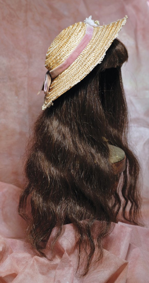 ANTIQUE DOLL WIG AND STRAW BONNET. Brunette long human: ANTIQUE DOLL WIG AND STRAW BONNET. Brunette long human hair wig with bangs and softly falling loose waves, includes cardboard pate; plus woven natural straw bonnet with velvet band and ivory flowers,