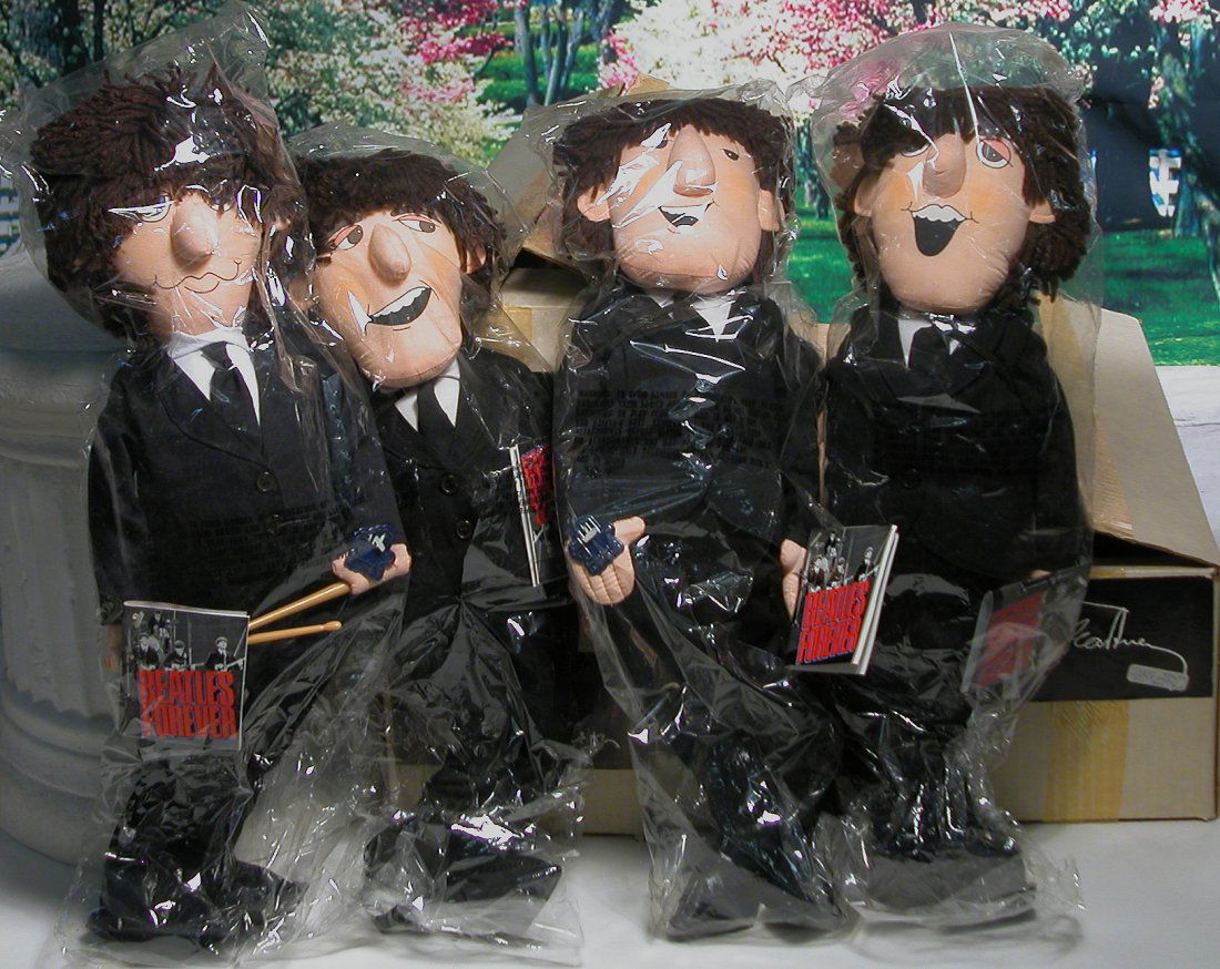 SET OF “BEATLES FOREVER” DOLLS BY APPLAUSE – NEVER: SET OF “BEATLES FOREVER” DOLLS BY APPLAUSE – NEVER REMOVED FROM PACKAGE. All-cloth portraits of the famous group, printed faces, yarn hair, limber cloth body, black cotton suits, black boots, in