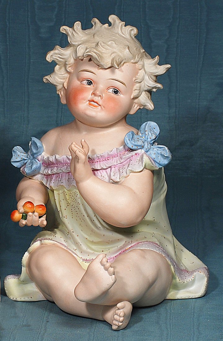 CONTA AND BOEHME LARGEST BISQUE PIANO BABY WITH FRUIT.: CONTA AND BOEHME LARGEST BISQUE PIANO BABY WITH FRUIT. Marks: Germany and faded Conta blue stamp. 15”. Seated bisque child has sculpted light blonde hair, painted features, deep intaglio blue eyes,