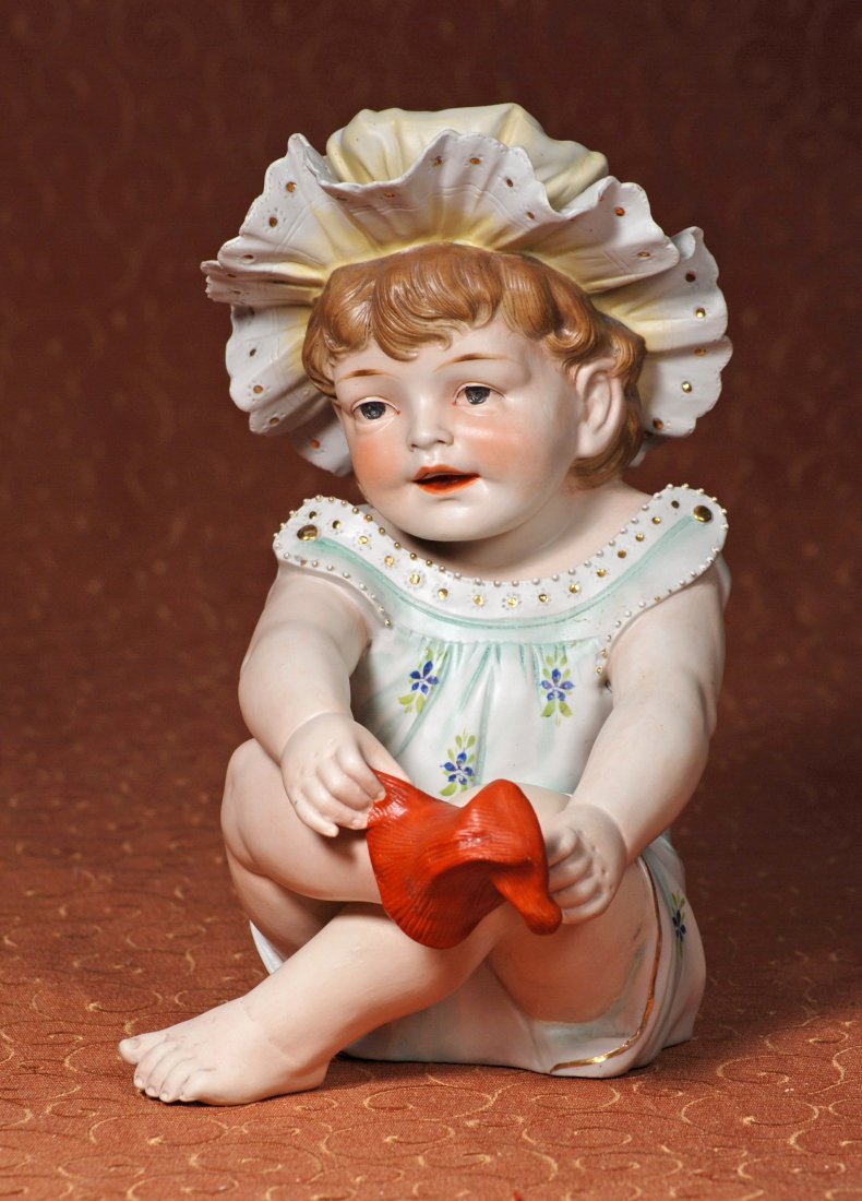 LARGE CONTA & BOEHME GERMAN BISQUE PIANO BABY PLAYING: LARGE CONTA & BOEHME GERMAN BISQUE PIANO BABY PLAYING WITH SOCK. 11”. Seated baby with deeply-sculpted face and brown hair, blue eyes, shaded brows, open/closed mouth with modeled detail between sha