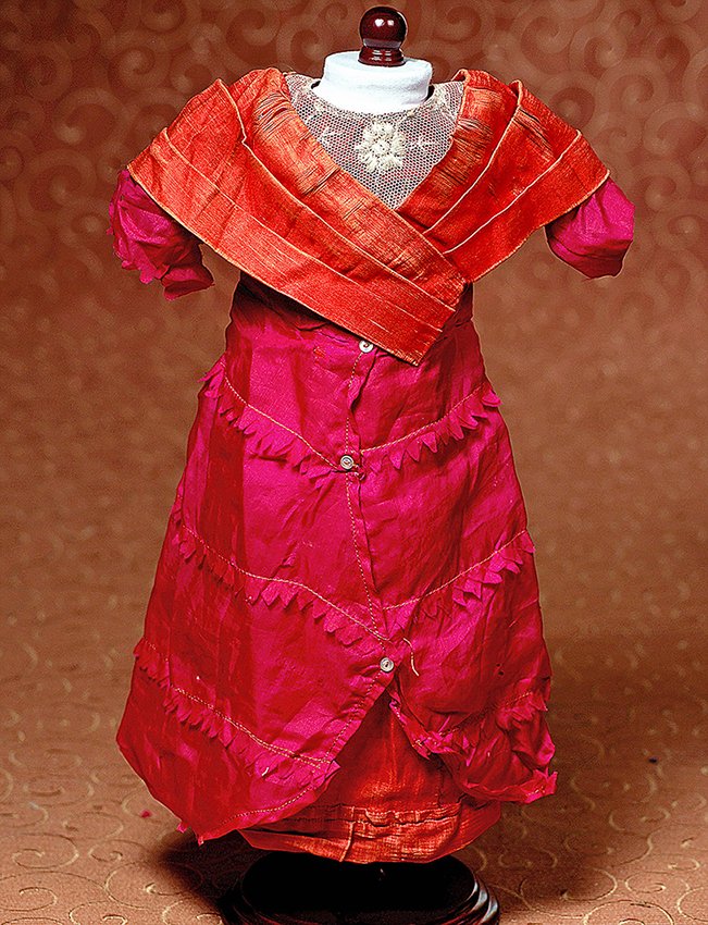 ANTIQUE SILK DOLL DRESS: ANTIQUE SILK DOLL DRESS. Fuchsia silk satin dress with princess styling, has inset lace bodice panel with criss-cross bands of red silk satin, skirt has four panels of fuchsia silk with pinked edges o