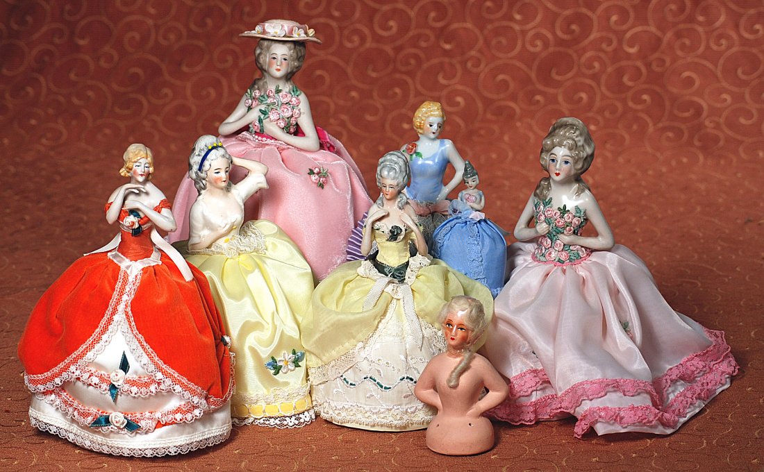 NINE HALF DOLLS: NINE HALF DOLLS. Includes one bisque and seven porcelain dolls with painted hair and features, mounted on bases with new clothing; two with arms away; plus one papier mache doll with painted features 