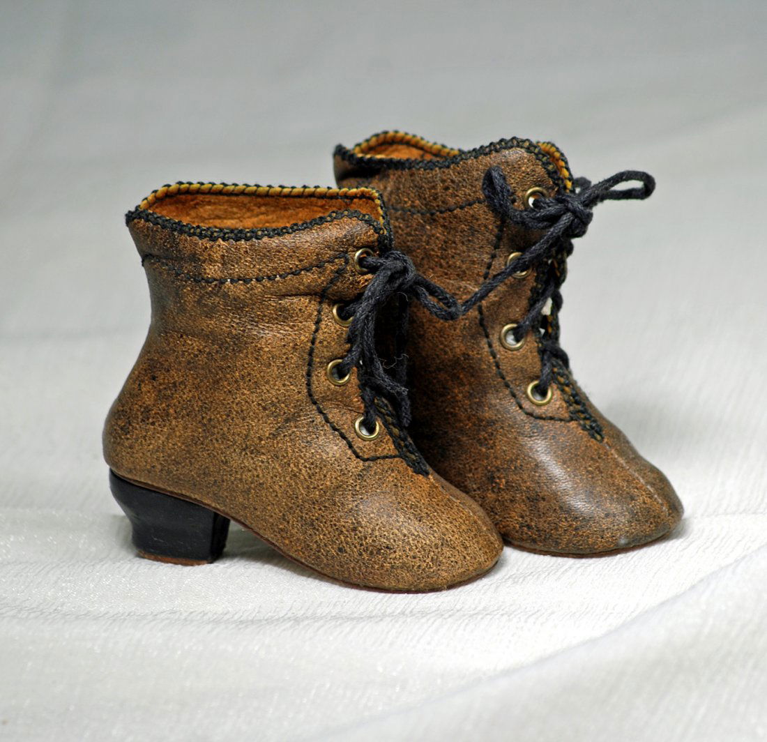 PAIR OF BROWN LEATHER FASHION BOOTS. 3 ” l. Brown: PAIR OF BROWN LEATHER FASHION BOOTS. 3 ” l. Brown leather boots have decorative black stitched edging, four pairs of brass lacing grommets, black laces, ” H. black heels. Commentary: Late 19th cen
