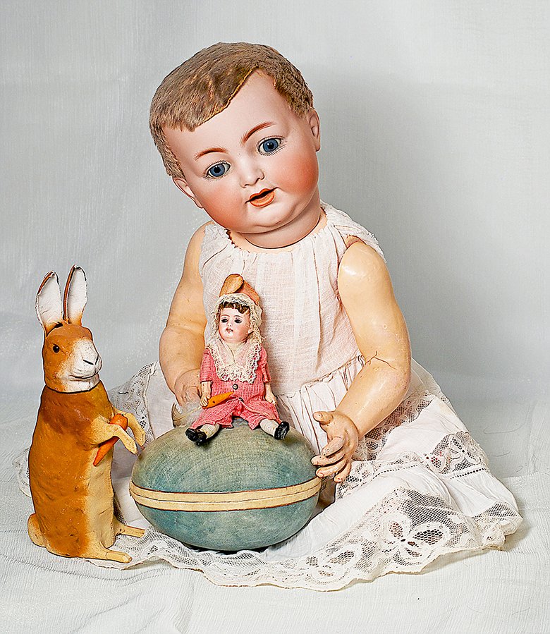 GERMAN BISQUE-HEAD DOLL ON EASTER EGG AS CANDY: GERMAN BISQUE-HEAD DOLL ON EASTER EGG AS CANDY CONTAINER. 10”. A bisque-head girl with brown glass eyes, open mouth, four teeth, brown mohair wig, wooden block torso, papier mache arms and legs, pai