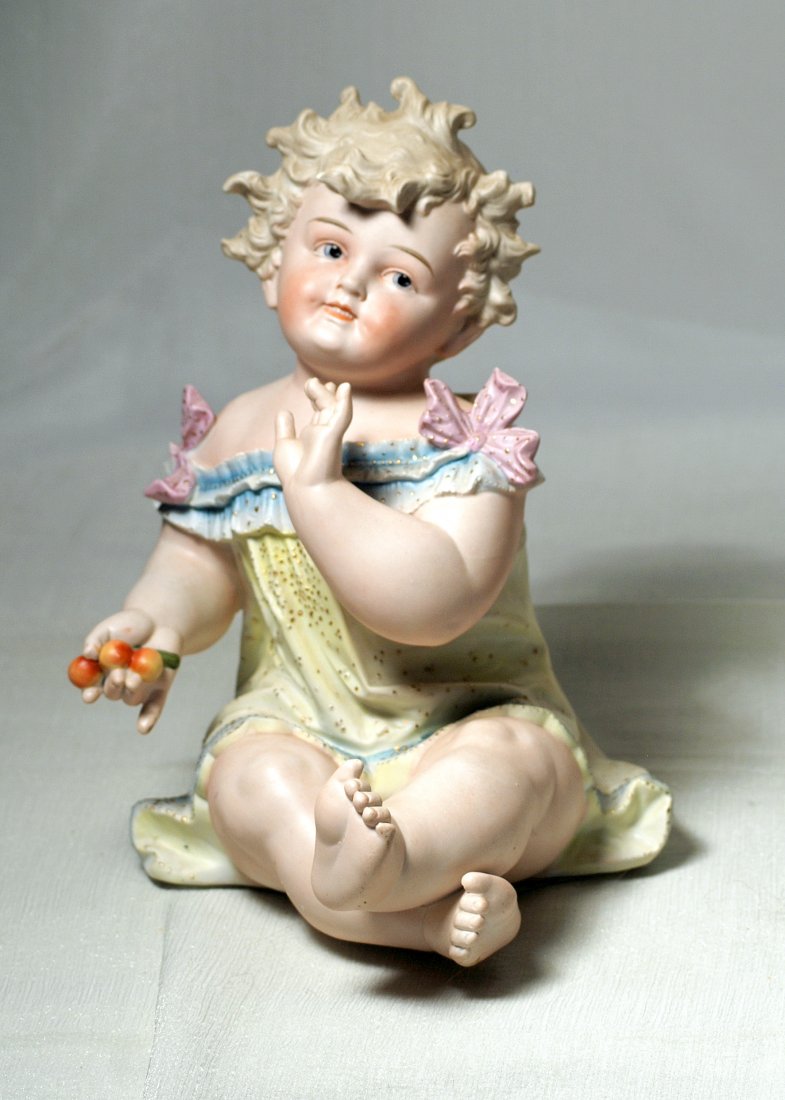 CONTA AND BOEHME LARGE BISQUE PIANO BABY.. Marks: None.: CONTA AND BOEHME LARGE BISQUE PIANO BABY.. Marks: None. 11”. Seated bisque child has sculpted light blonde hair, painted features, deep intaglio blue eyes, red and black lid lines, shaded and tapere