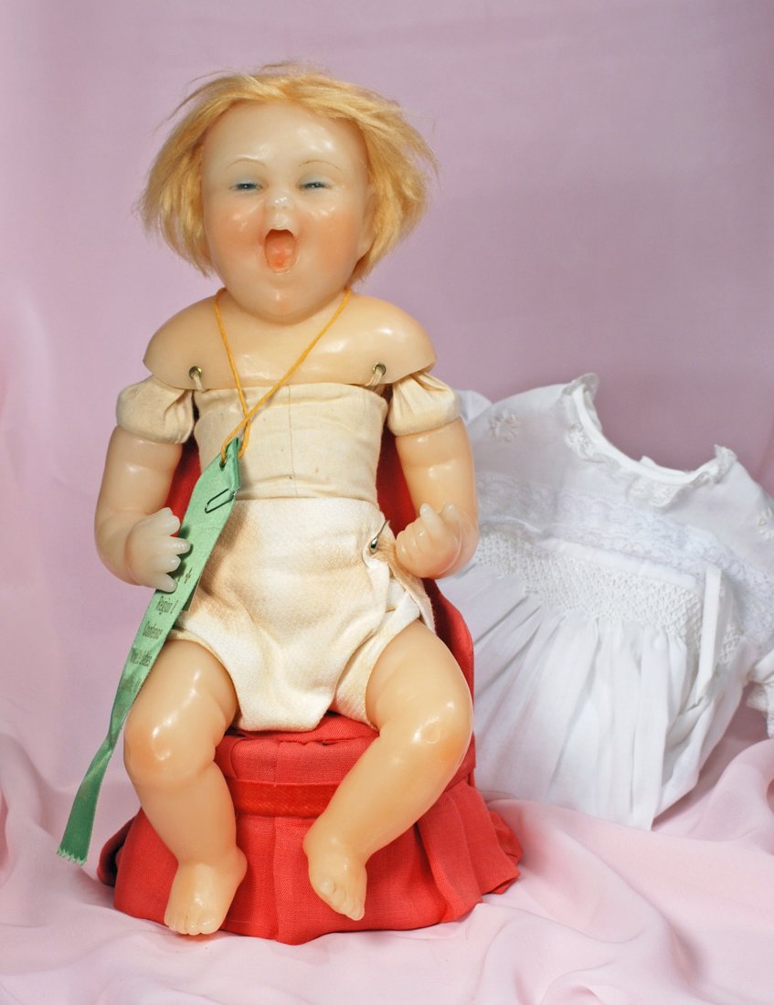 POURED WAX CRYING BABY WITH GLASS EYES: POURED WAX CRYING BABY WITH GLASS EYES. 16”. Poured wax shoulderhead with inset narrow blue glass eyes, painted lashes, feathered brows, open mouth with painted tongue, inset blonde mohair wig, clot