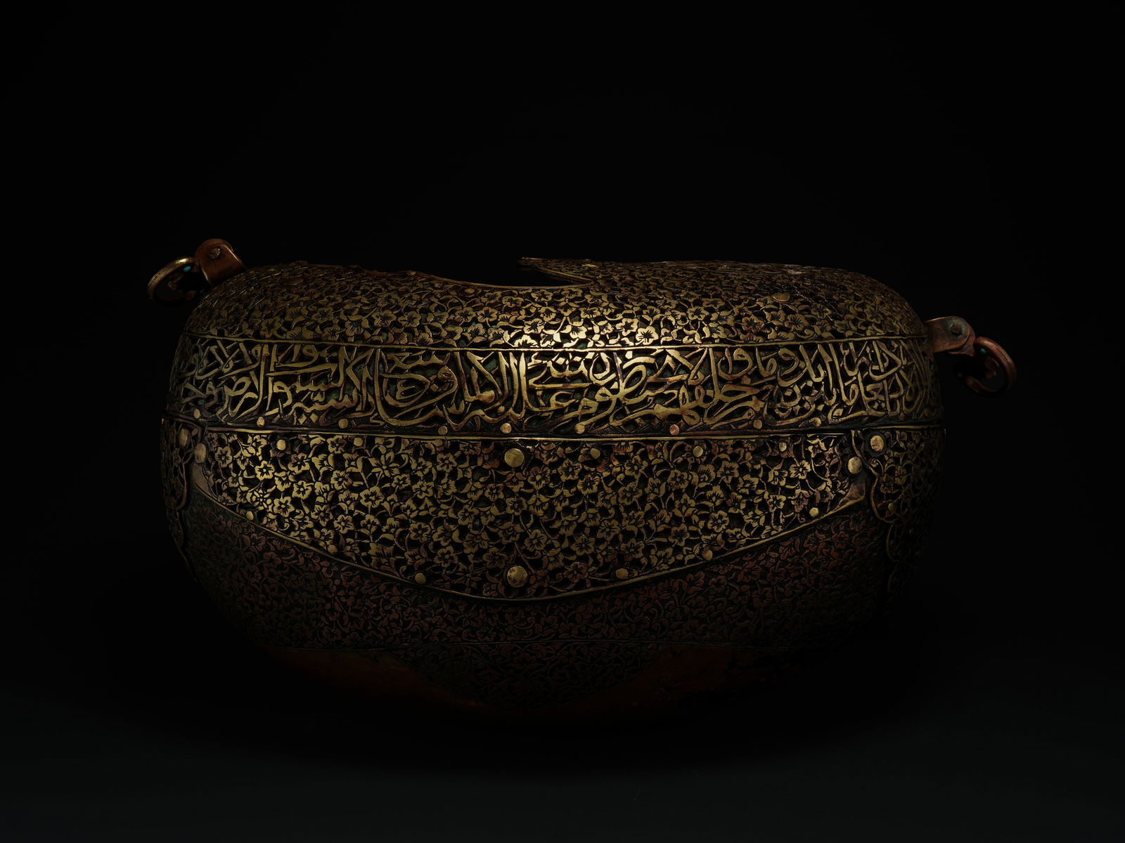 A Qajar Pierced Copper and Brass Kashkul Beggar's Bowl, 19th Century.: An oval-form Islamic kashkul beggarÃ¢â‚¬â„¢s bowl crafted from brass, richly decorated across its surface with dense, finely worked floral motifs arranged in continuous fields. The exterior