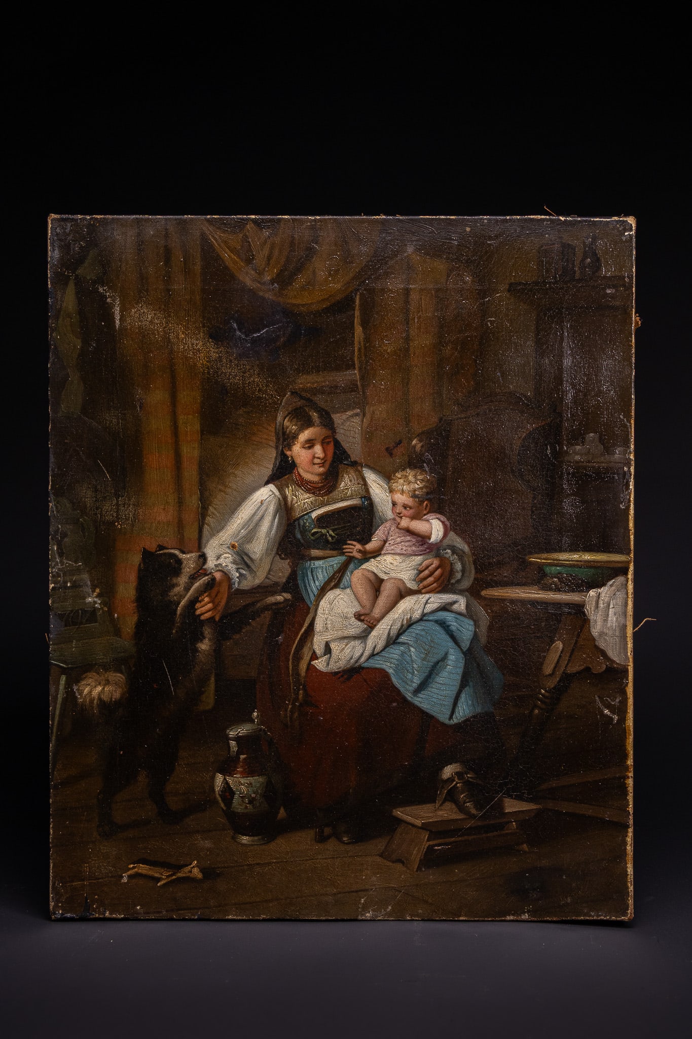 GERMAN SCHOOL, 19TH CENTURY, MOTHER AND CHILD IN A RUSTIC INTERIOR.: This 19th-century oil on canvas depicts a maternal genre scene set within a rustic interior, characteristic of the German School. The central focus is a young woman in traditional folk costume, featur