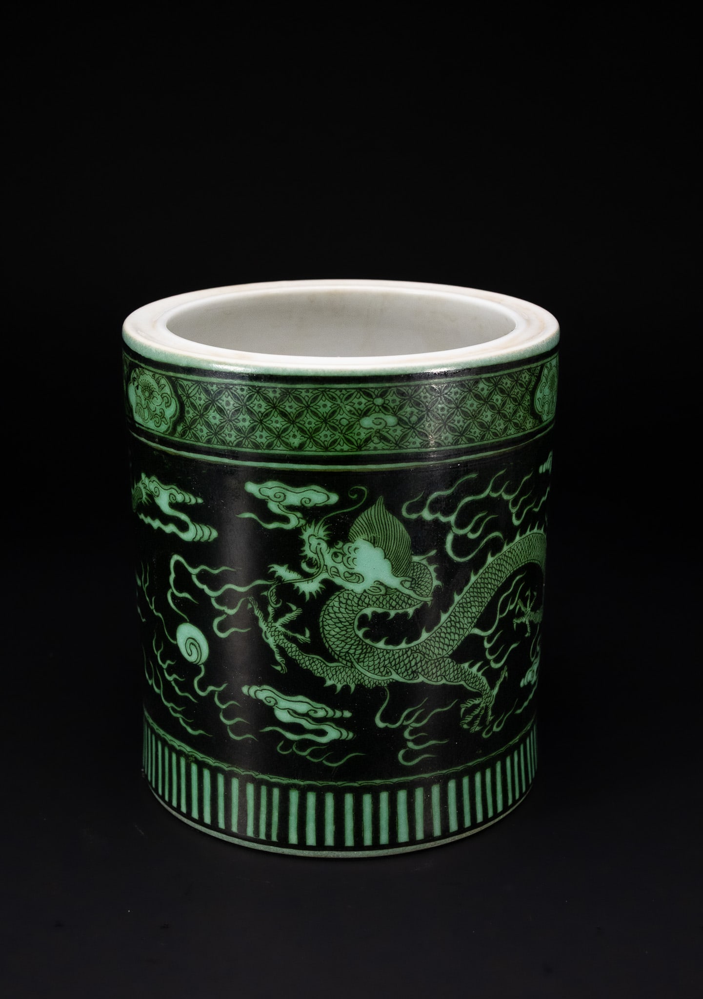 A CHINESE GREEN-ENAMELLED BLACK-GROUND DRAGON BRUSH POT, BITONG.: A porcelain brush pot of cylindrical form, known as a bitong, decorated in green enamels over a black ground. The exterior is decorated with a five-clawed imperial dragon pursuing a flaming pearl amon