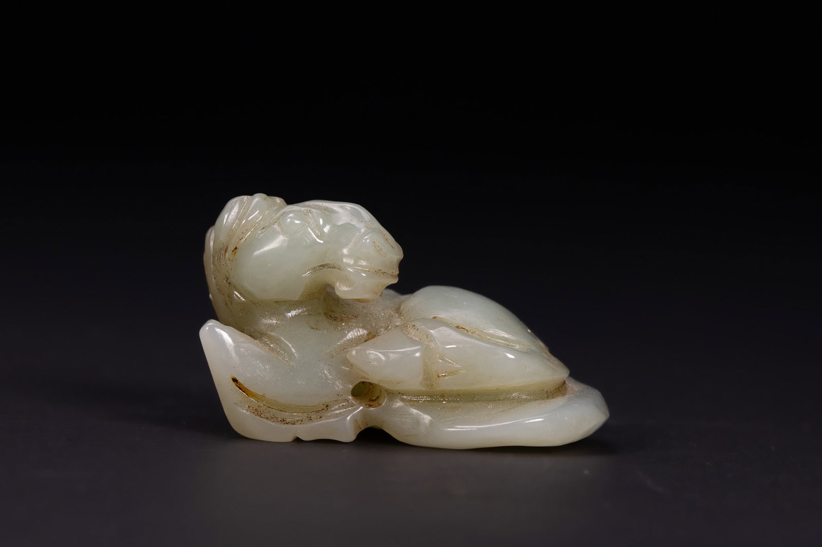 A CHINESE PALE CELADON JADE CARVING OF A RECUMBENT HORSE. (1 of 3)
