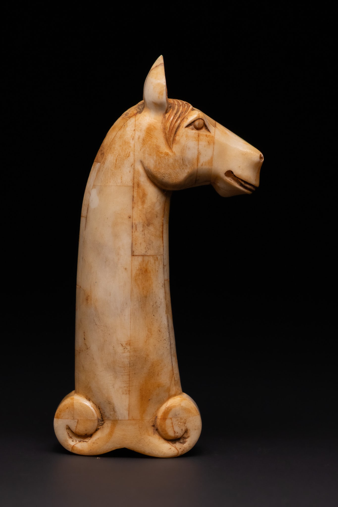 AN INDIAN MUGHAL BONE HORSE-HEAD DAGGER HILT, 19TH CENTURY OR LATER.: A carved bone dagger hilt fashioned in the form of a horse's head with elongated neck and finely incised mane. The head features carved eyes, ears and muzzle, while the lower section terminates in a s