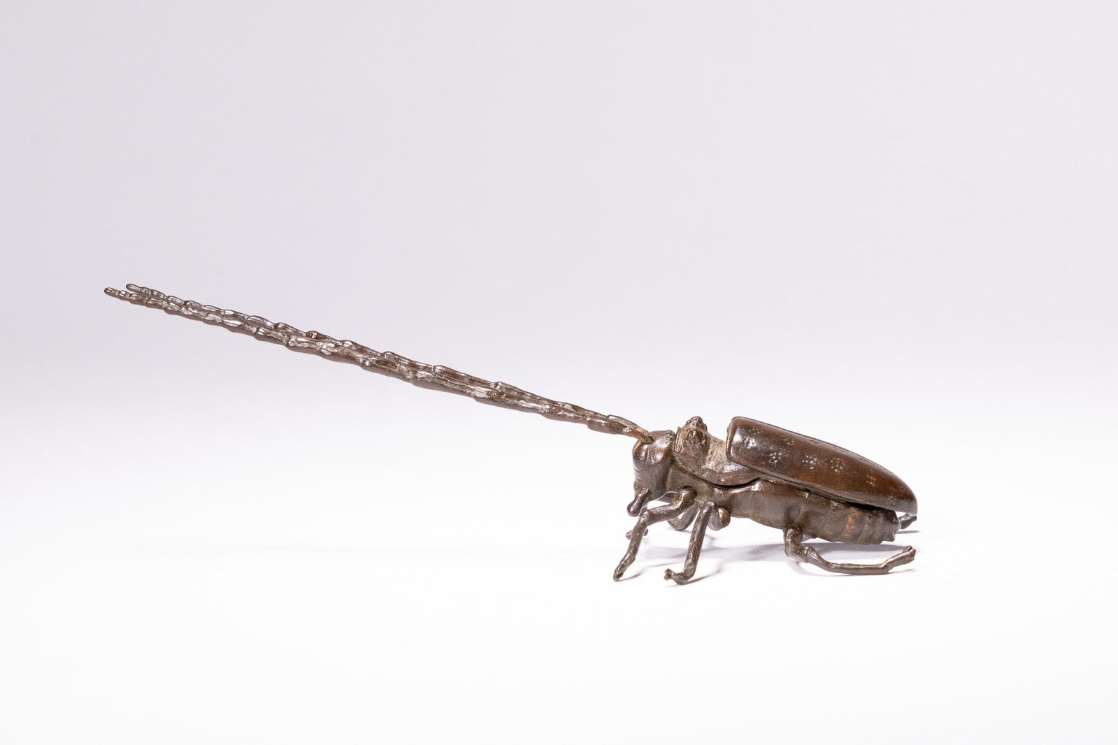 A JAPANESE ARTICULATED BRONZE LONGHORN BEETLE JIZAI OKIMONO SIGNED MYOCHIN.: A Japanese articulated bronze model of a longhorn beetle, known as a kamikiri, produced during the late Meiji period. This jizai okimono is realistically cast with a segmented body and finished with a