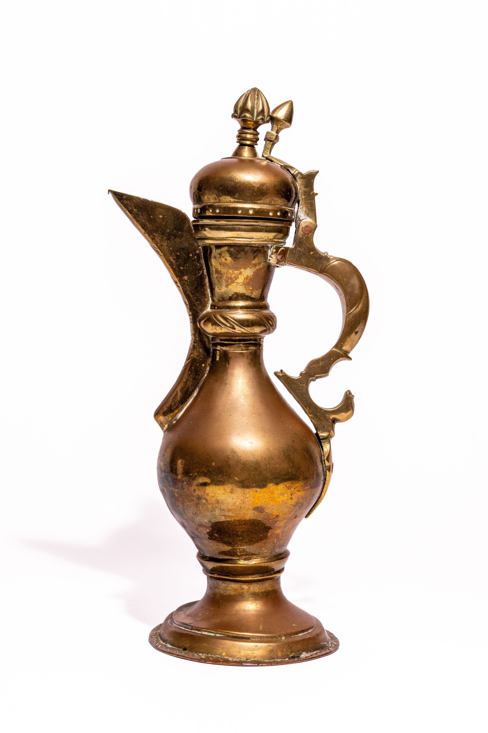 A BUKHARA BRASS DALLA COFFEE POT, CIRCA LATE 19THâ€“EARLY 20TH CENTURY.: A distinctive Bukhara brass dalla coffee pot, of elegant baluster form, the rounded body raised on a spreading circular foot and surmounted by a domed hinged cover with a stylised bud-form finial. The