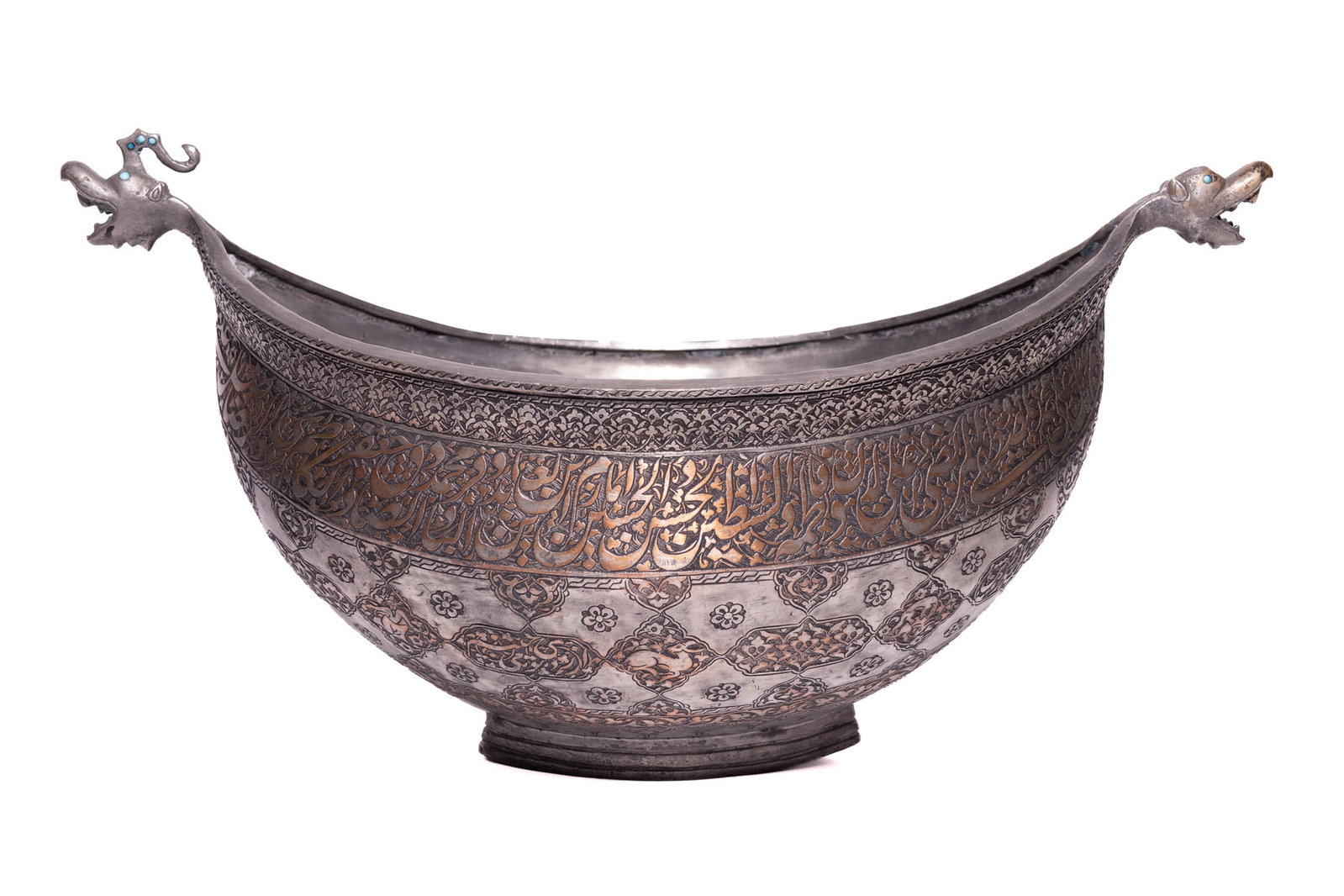 A LARGE SAFAVID TINNED COPPER SUFI KASHKUL, 17TH CENTURY.: A Persian tinned copper kashkul, or dervish's begging bowl, of traditional boat-shaped form. The exterior is decorated with a combination of chasing, engraving, and metal inlay. A broad central frieze