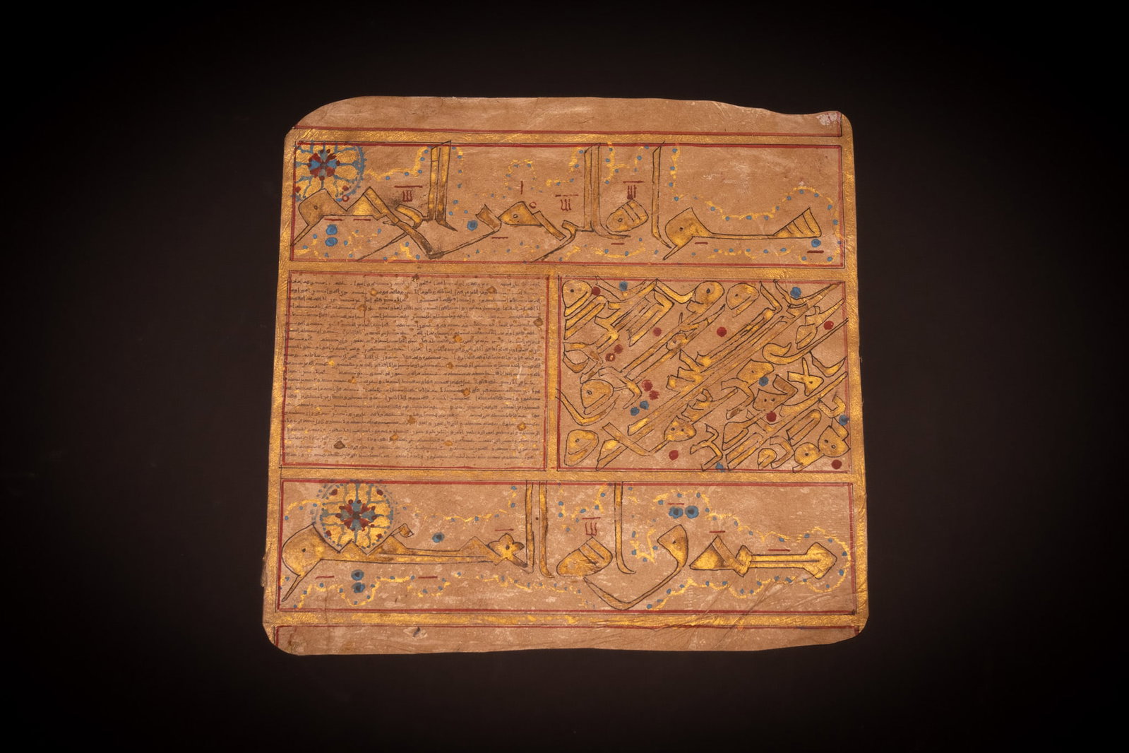 AN ILLUMINATED QUR'AN MANUSCRIPT LEAF ON VELLUM. MIDDLE EAST OR NORTH AFRICA, CIRCA 18TH-19TH: A single illuminated manuscript leaf on vellum, likely of Middle Eastern or North African origin. The leaf is organised into four distinct panels defined by red and gold border lines. The upper and lo