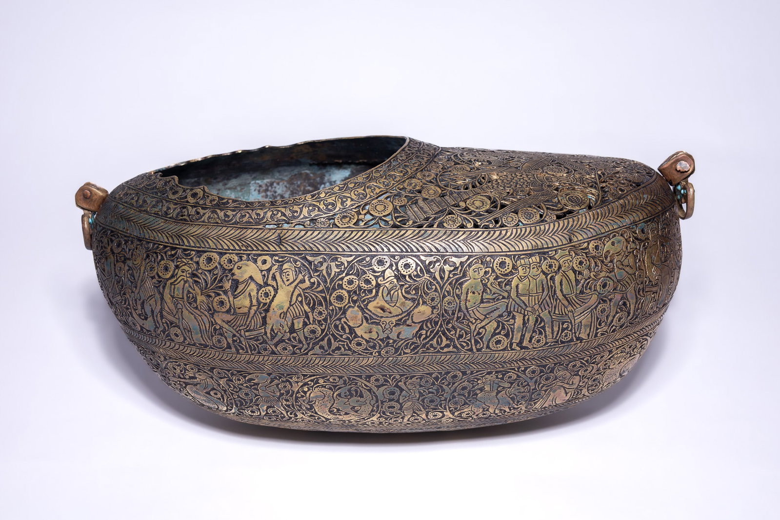 A QAJAR BRASS KASHKUL BEGGARS BOWL WITH OPENWORK DECORATION.: This Persian kashkul, or beggars bowl, is fashioned from brass in a traditional boat-like form. The upper surface is largely occupied by an integral panel of pierced openwork, featuring a central eigh