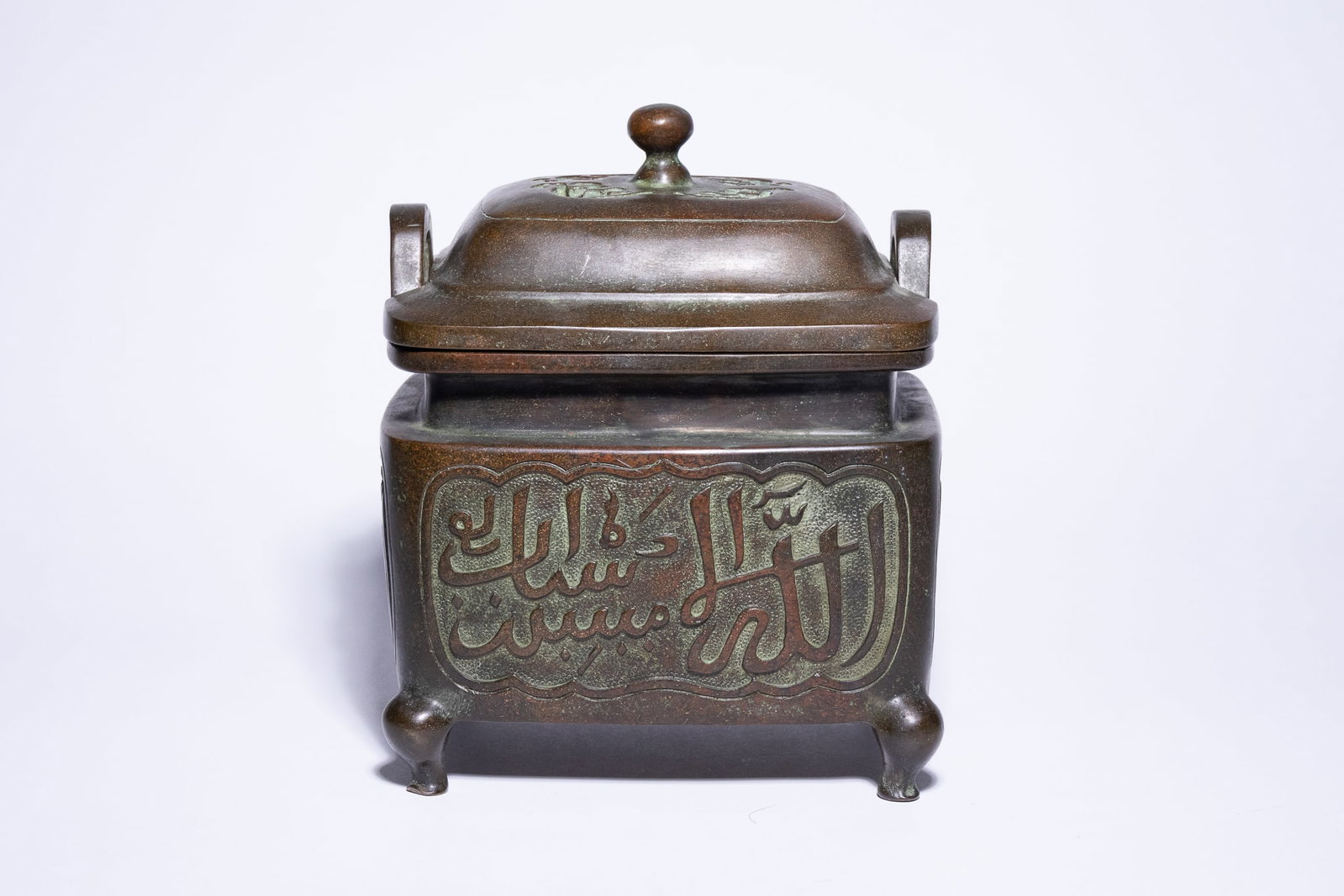 A CHINESE BRONZE ISLAMIC MARKET CENSER AND COVER, XUANDE MARK.: A Chinese cast bronze incense burner of rectangular section, featuring a conforming domed cover. The body is decorated with four lobed panels, each cast with Arabic calligraphy in raised relief set ag