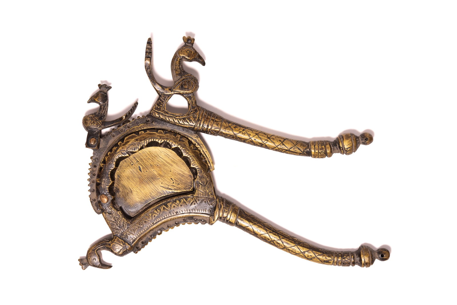A NORTH INDIAN BRASS SAROTA BETEL NUT CUTTER WITH PEACOCK MOTIFS, 19TH CENTURY.: A North Indian betel nut cutter, known as a sarota, fashioned from cast and hand-incised brass. The object features three stylised peacock (mayura) figures; one is located on the hinge, one serves as 