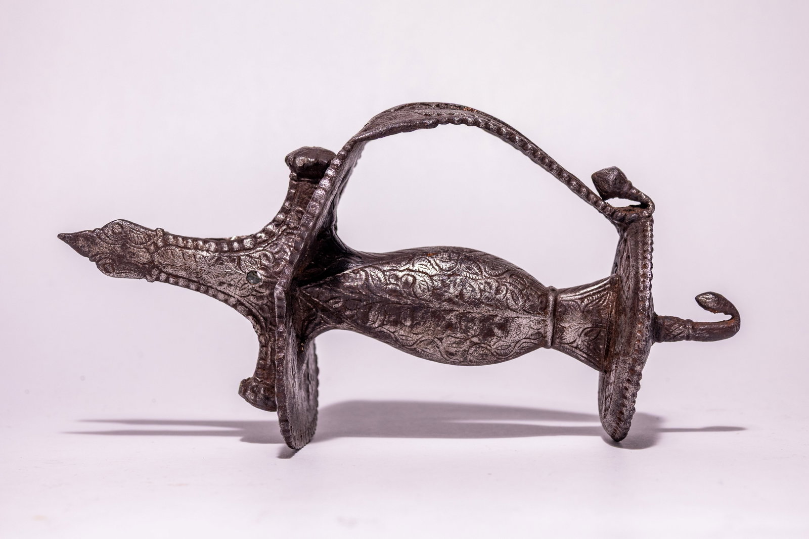 A MUGHAL OR SIKH CHISELLED IRON TULWAR SWORD HILT, 17TH CENTURY.: This is a17th century Indian tulwar sword hilt of forged and chiselled iron construction. The hilt follows a traditional Indo-Persian form, featuring a central grip with a bulbous midsection flanked b