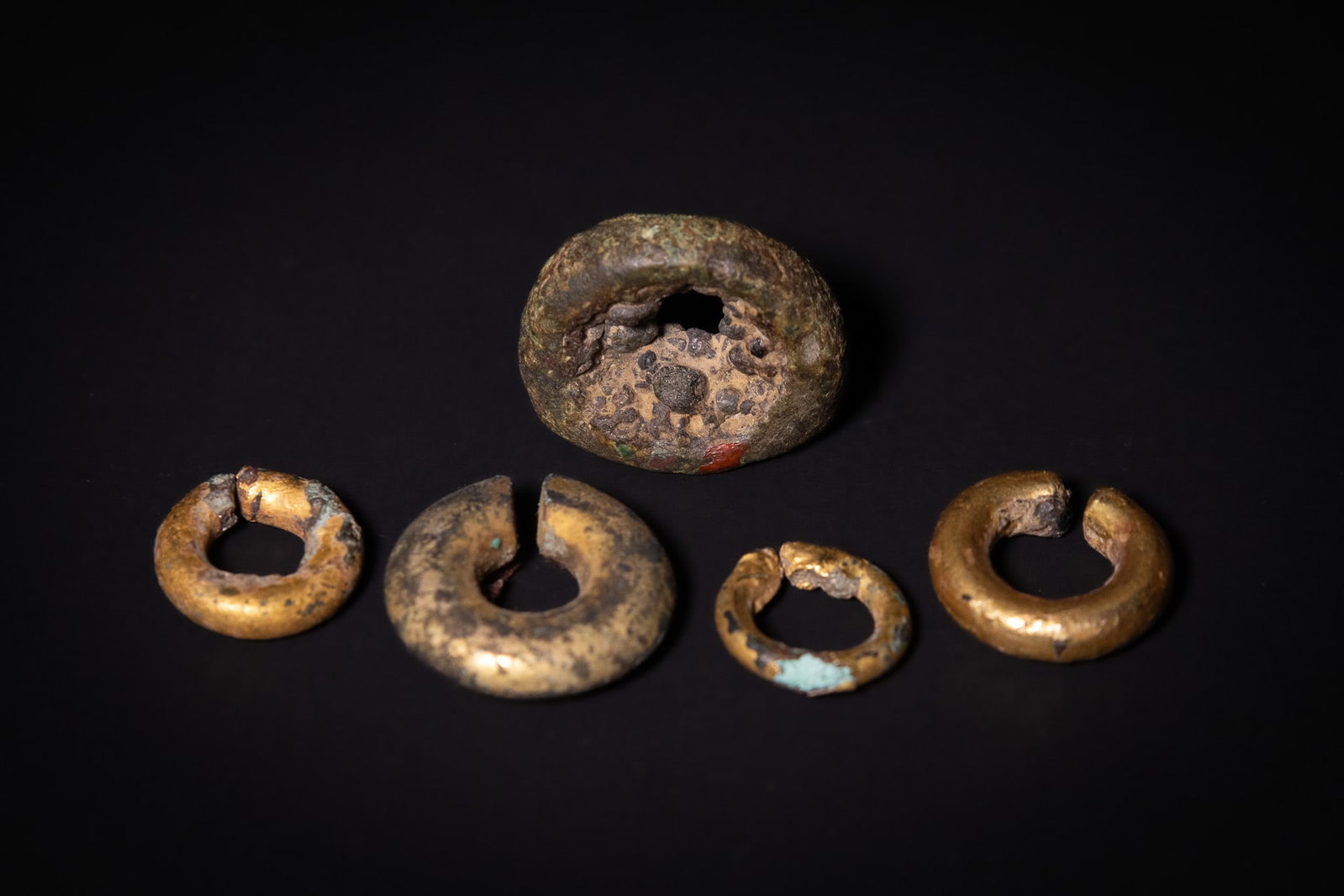AN EARLY INDIAN COPPER SIGNET RING AND FOUR GOLD GILT-COPPER ORNAMENTS, CIRCA 1ST CENTURY: A group of five early Indian metal ornaments, comprising a substantial copper signet ring or seal together with four circular ornaments of varying sizes, traditionally dated to approximately 2,000 yea