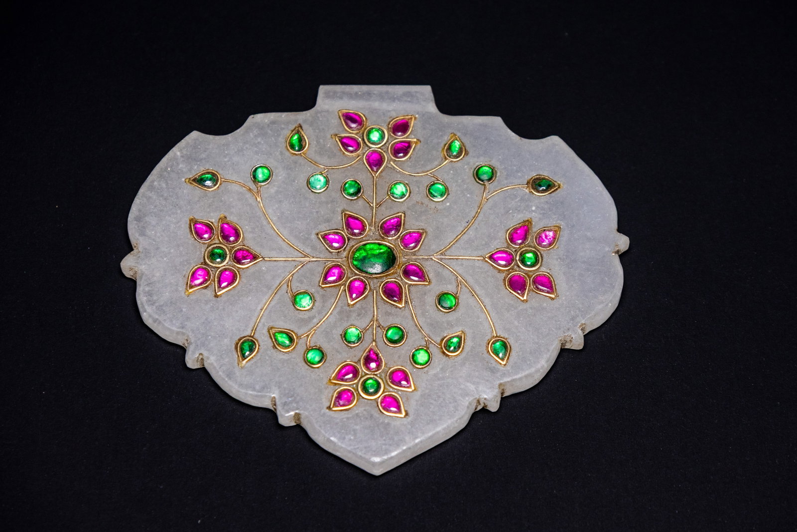 A MUGHAL STYLE GEM-SET NEPHRITE JADE HALDILI PENDANT.: A heart-shaped plaque carved from translucent pale greyish-white nephrite jade, traditionally known as a haldili, following the North Indian and Rajasthan Mughal tradition. The obverse is decorated wi