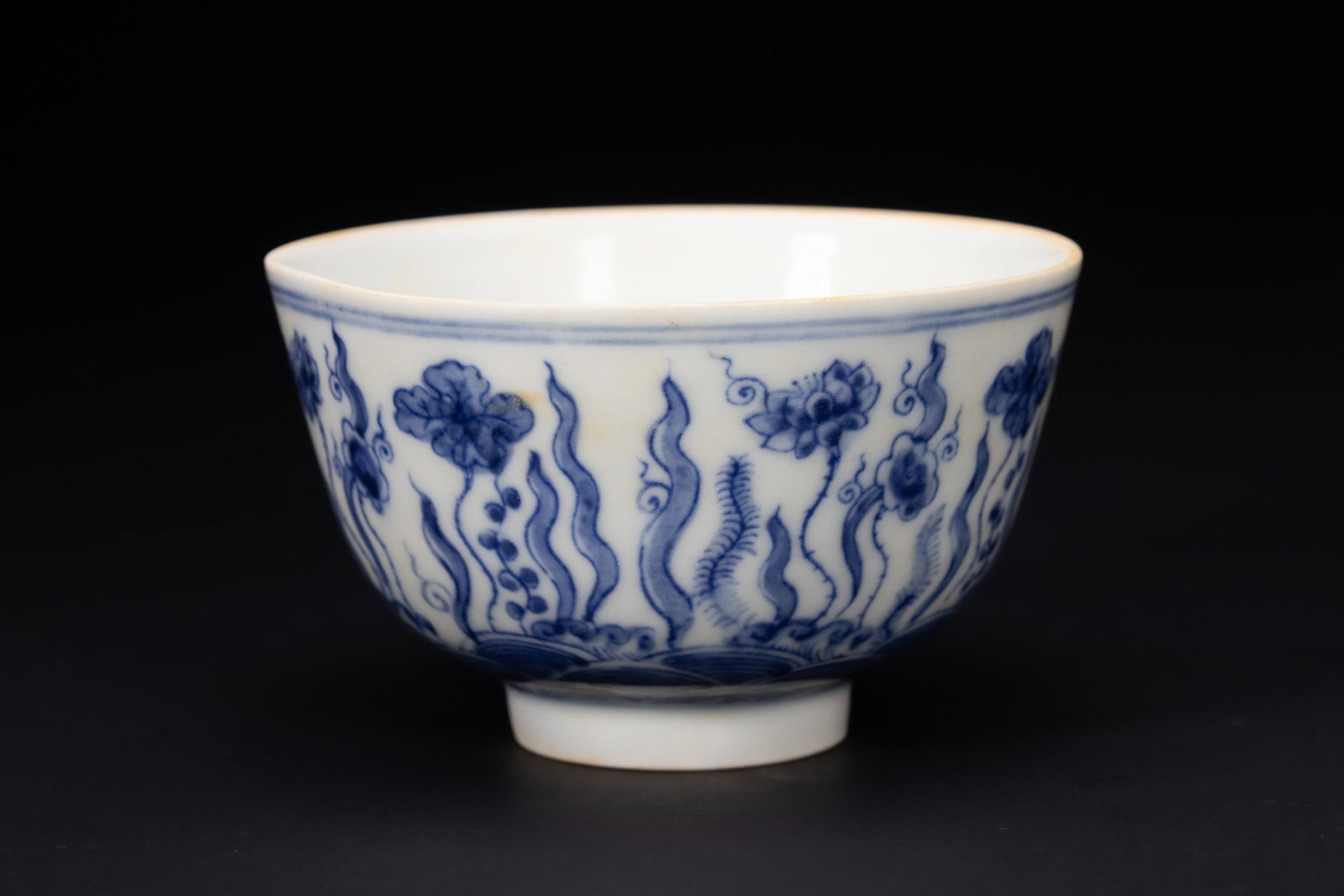 A CHINESE BLUE AND WHITE PORCELAIN 'LOTUS POND' BOWL.: A Chinese porcelain bowl of rounded form, rising from a short, neatly finished foot to a gently flared rim. The exterior is decorated in underglaze cobalt blue with a continuous scene of stylised aqua