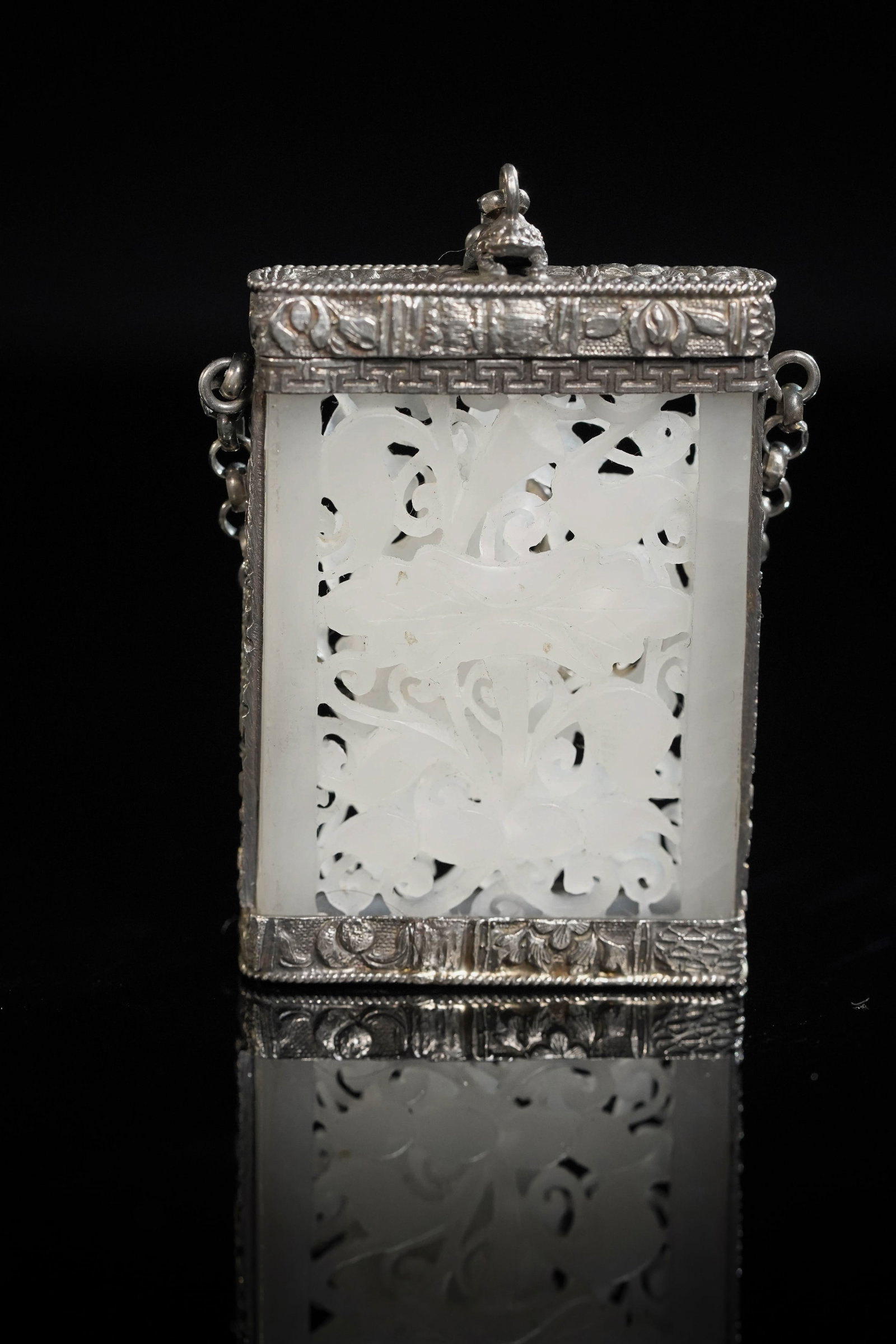 A CHINESE CARVED WHITE JADE PERFUME BOTTLE.: This Chinese perfume bottle features a finely carved white jade plaque with intricate openwork scrolling floral and foliate motifs. The rectangular jade panel is mounted within a frame, richly adorned