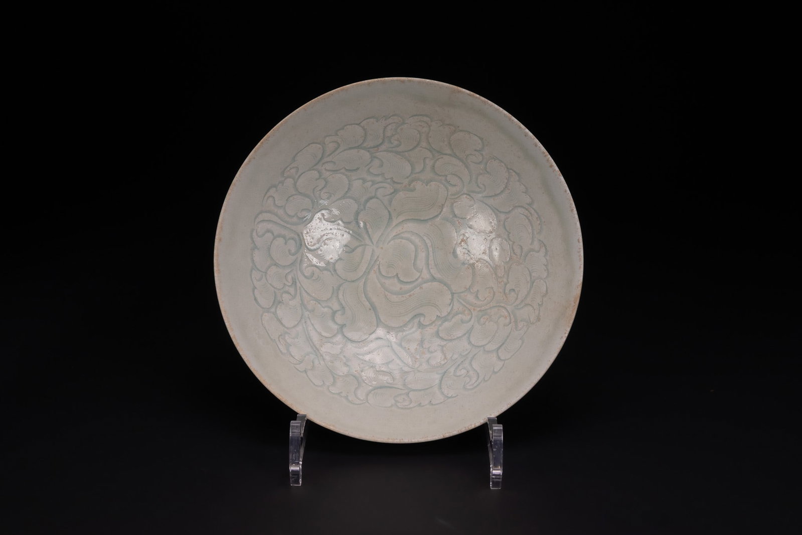 A CHINESE CARVED QINGBAI PORCELAIN BOWL, SOUTHERN SONG DYNASTY (1127-1279).: A Chinese porcelain bowl of shallow form, attributed to the Jingdezhen kilns of the Song to Yuan dynasty. The vessel is covered in a qingbai glaze of pale bluish-white tone, which pools to a deeper hu