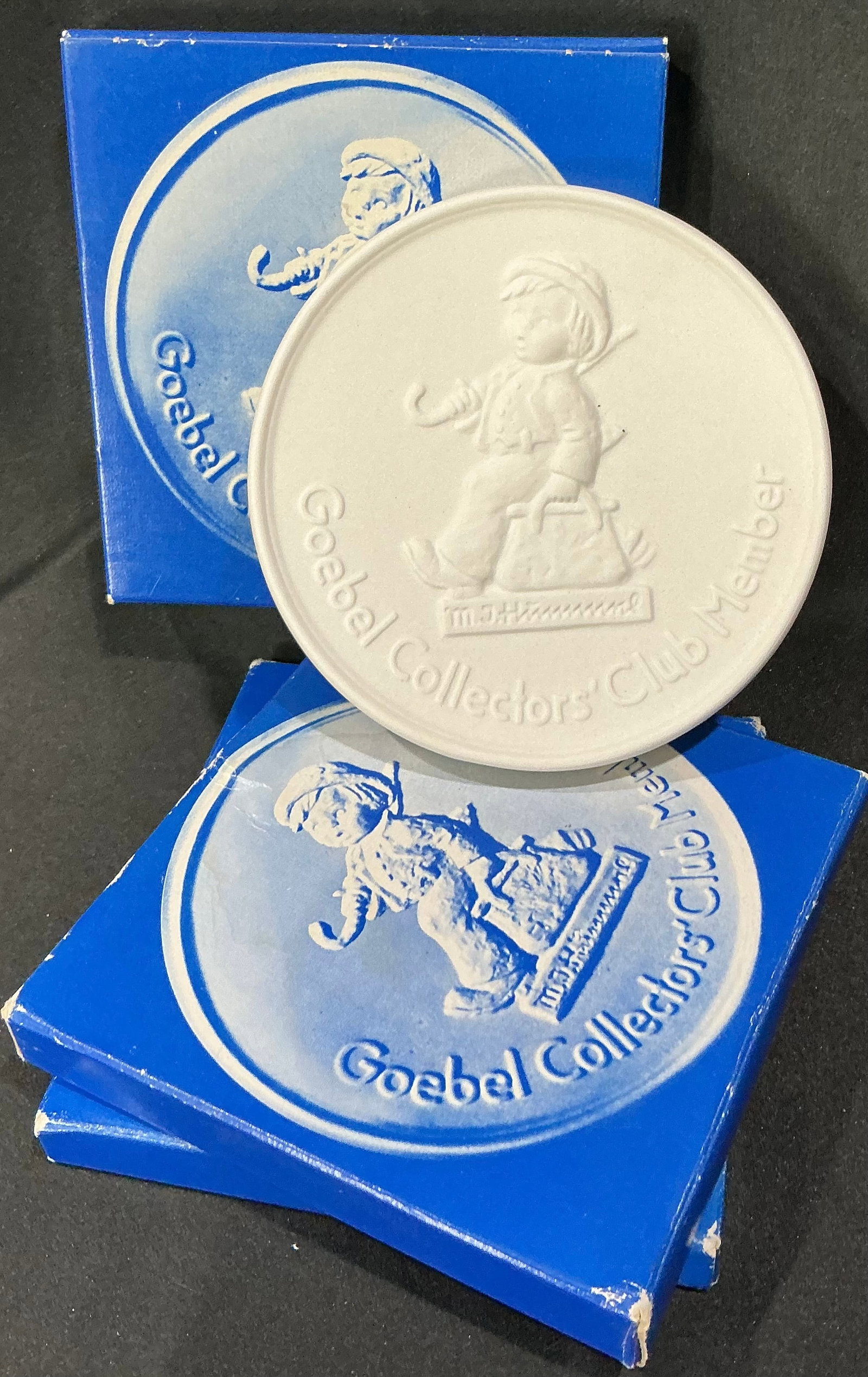 Set of (3) M.I. Hummel Goebel Collectors' Club Member Bas-Relief Plaques: Set of three Goebel Collectors' Club plaques with raised child motif; original blue presentation boxes.