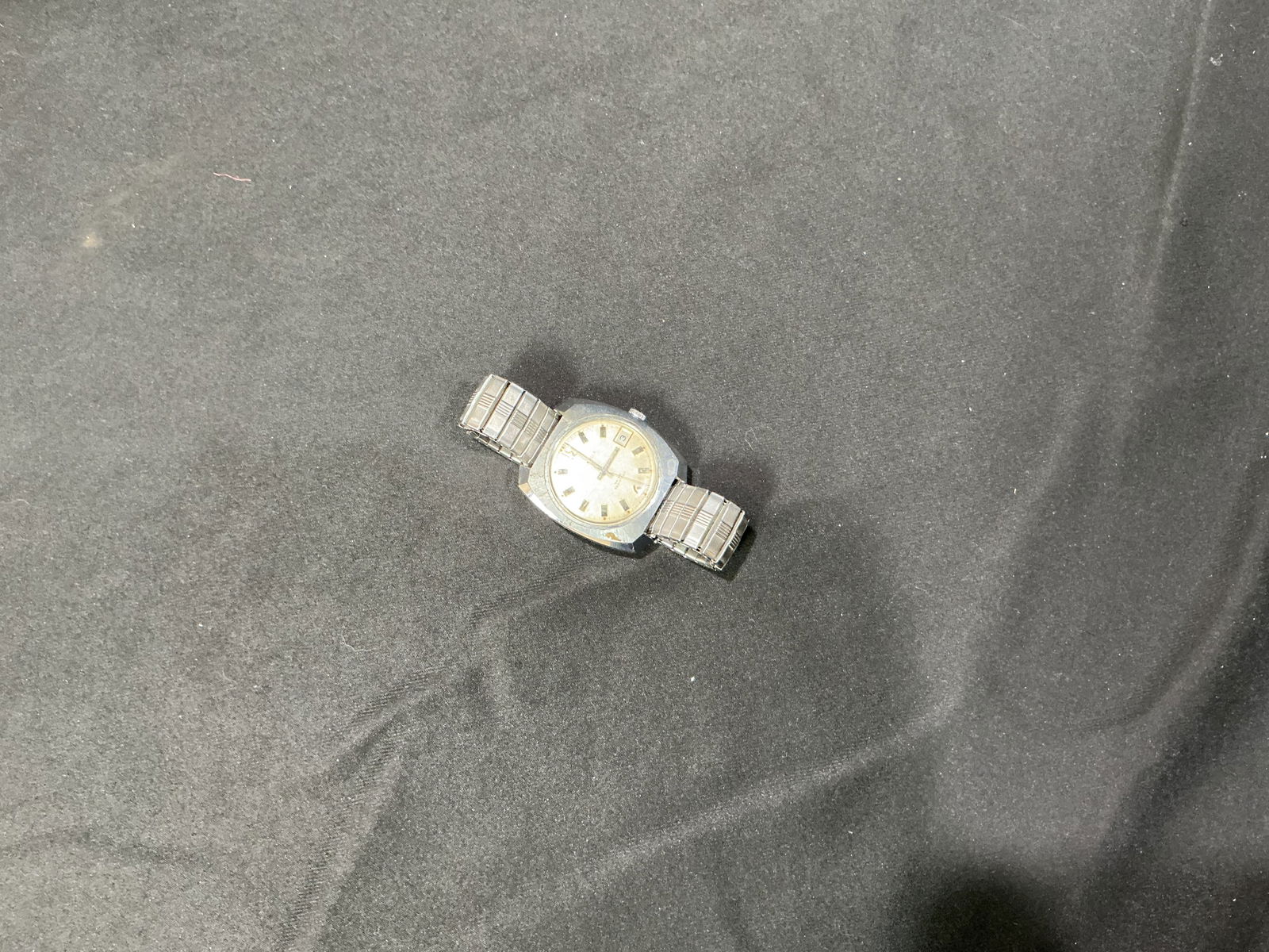 Vintage Stainless Steel Date Wristwatch (Brand Caravelle): Vintage stainless steel wristwatch with silver-tone dial, baton hour markers, central seconds, and date window at 3 o'clock. Fitted with a stretch/expansion metal bracelet. Untested for timekeeping ac