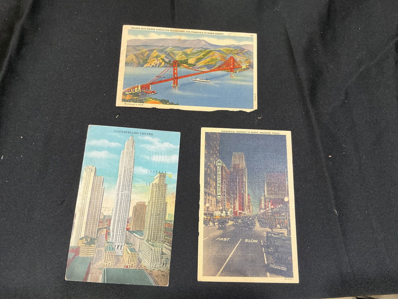 Set of Three Early 20th-Century 117 Landmark Postcards Golden Gate Bridge, Rockefeller Center,: Grouping of three vintage 117 city postcards depicting notable landmarks: the Golden Gate Bridge spanning San Francisco Bay, Rockefeller Center in New York City, and the Theatrical District at Night i