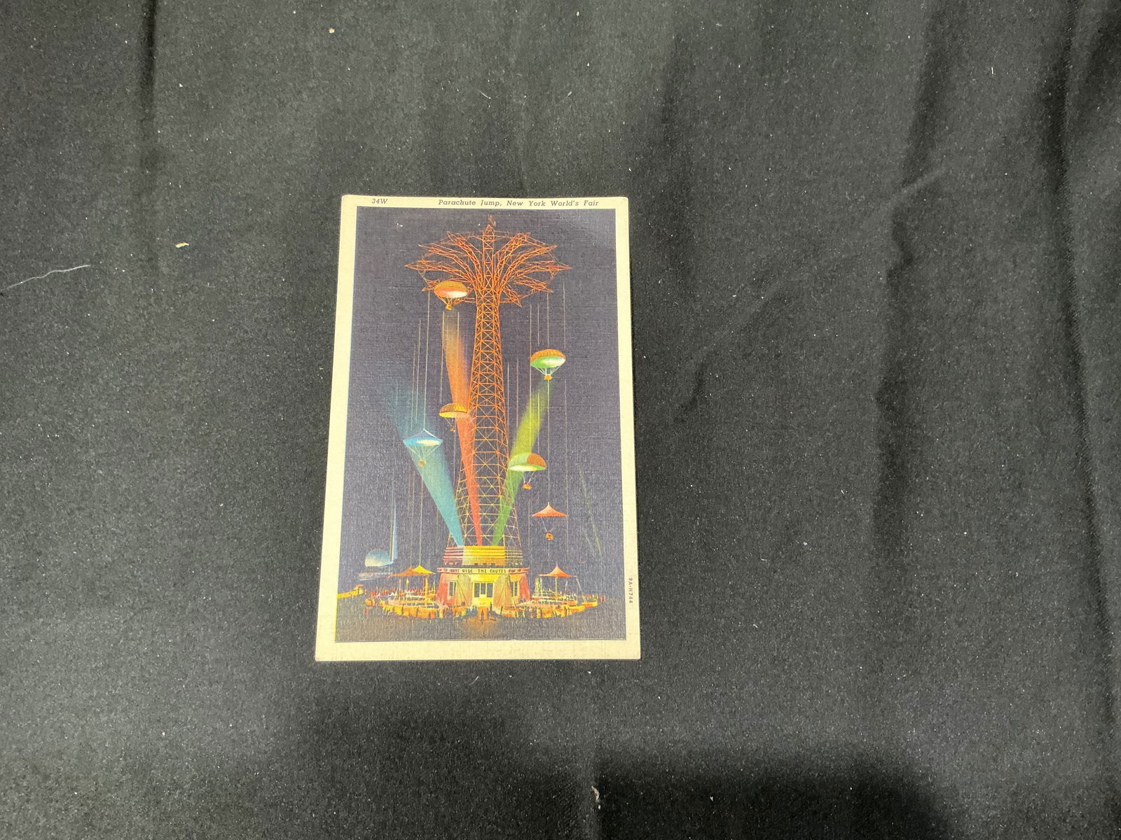 1939-40 New York World's Fair Parachute Jump Officially Licensed Postcard: Original 1939-40 New York World's Fair postcard depicting the iconic Parachute Jump illuminated at night. Officially licensed issue bearing the World's Fair logo and detailed printed description on ve