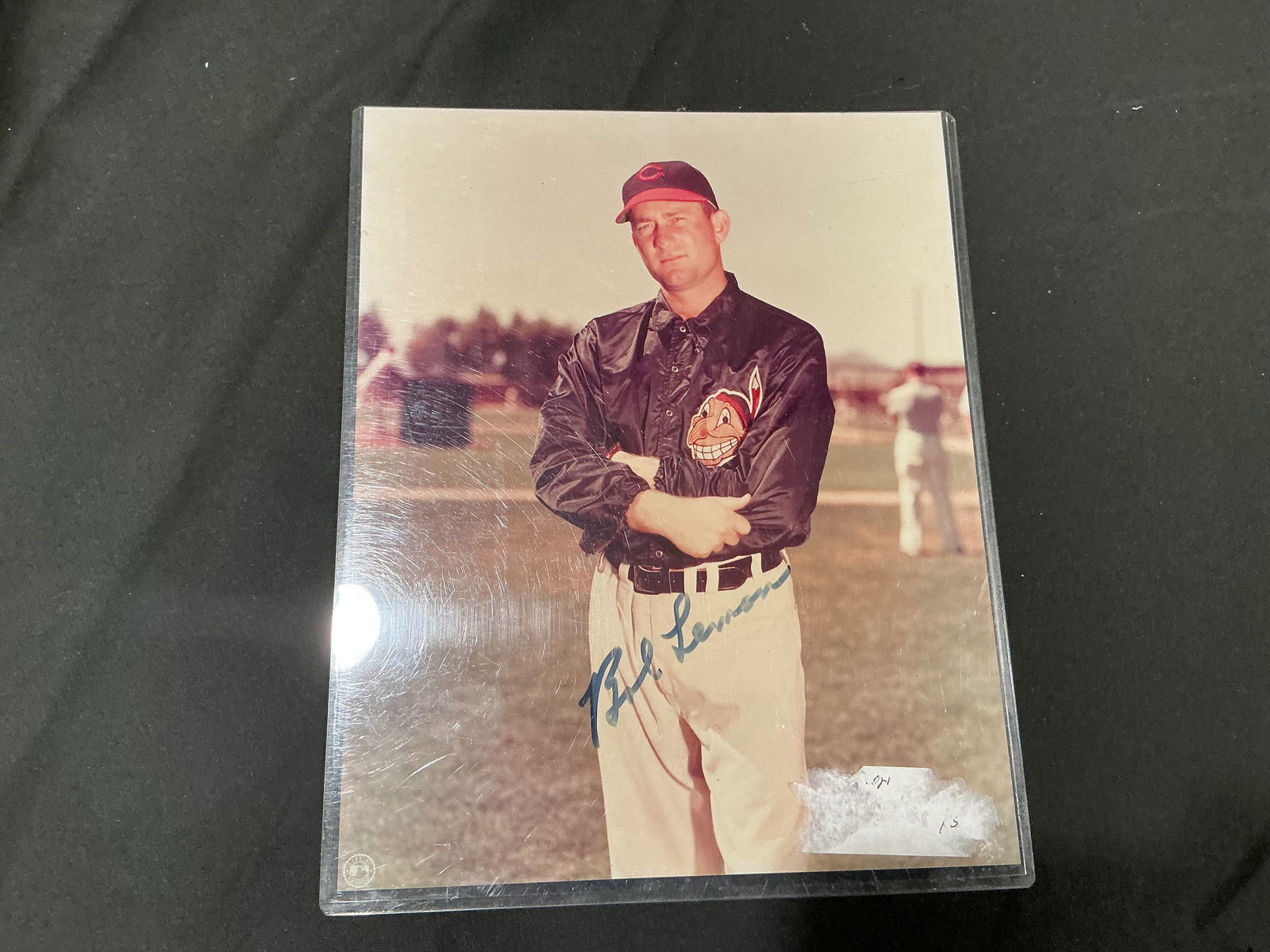 Bob Lemon Autographed Cleveland Indians Vintage Photo: Vintage color photograph of Hall of Fame pitcher Bob Lemon in Cleveland Indians warmup jacket, signed boldly across the lower portion. Encapsulated in protective sleeve.