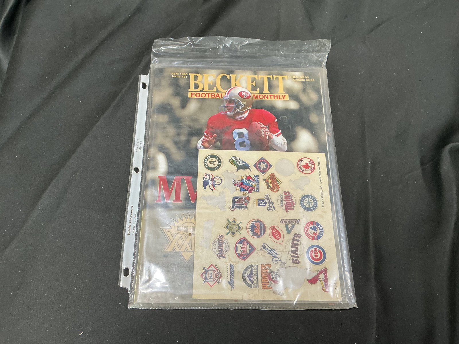 Sealed Beckett Football Card Monthly Magazine Lot – Steve Young & Buccaneers #32 Covers: Lot includes one sealed Beckett Football Card Monthly magazine kept in protective plastic/binder sleeve. One side appears to be April 1995 (Issue #61) featuring San Francisco 49ers QB Steve Young on t
