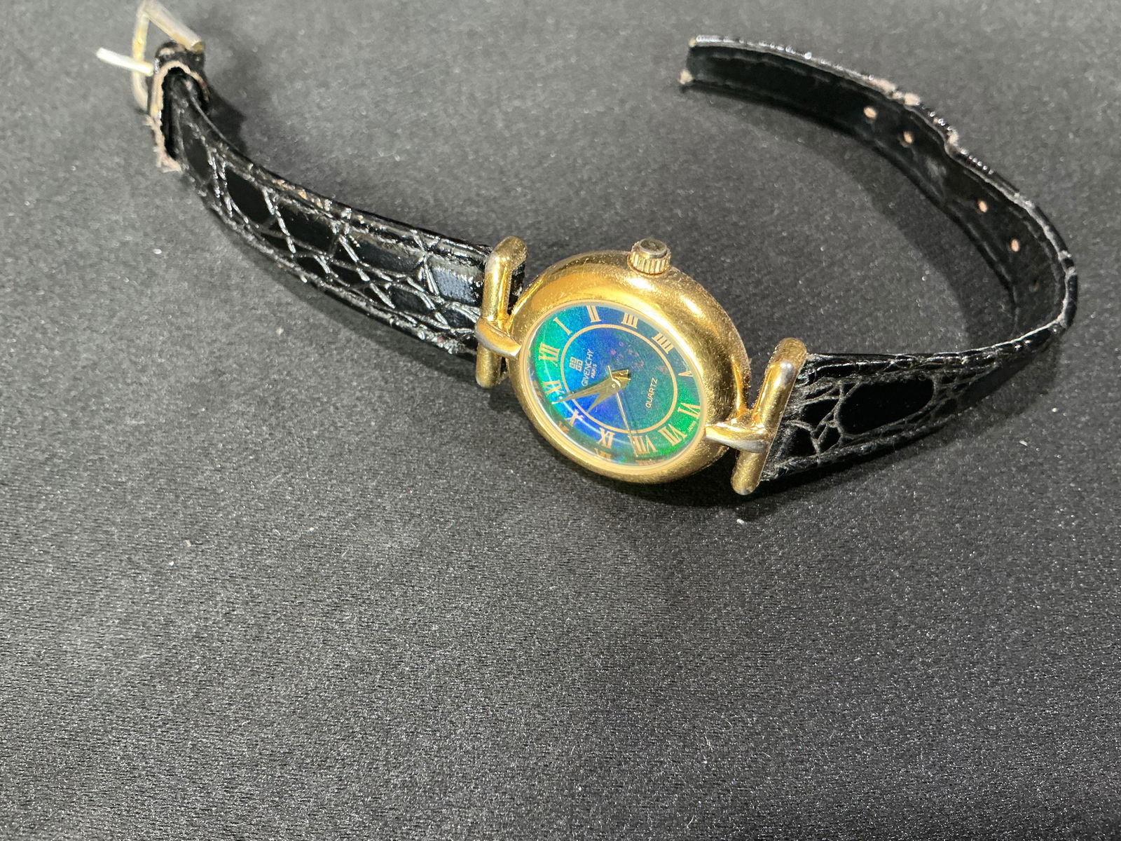 Givenchy Paris Ladies Quartz Wristwatch, Gold-Tone Case with Leather Strap: Ladies Givenchy Paris quartz wristwatch featuring a round gold-tone case with iridescent multicolor dial and Roman numeral hour markers. Signed Givenchy Paris dial. Fitted with a black leather strap.