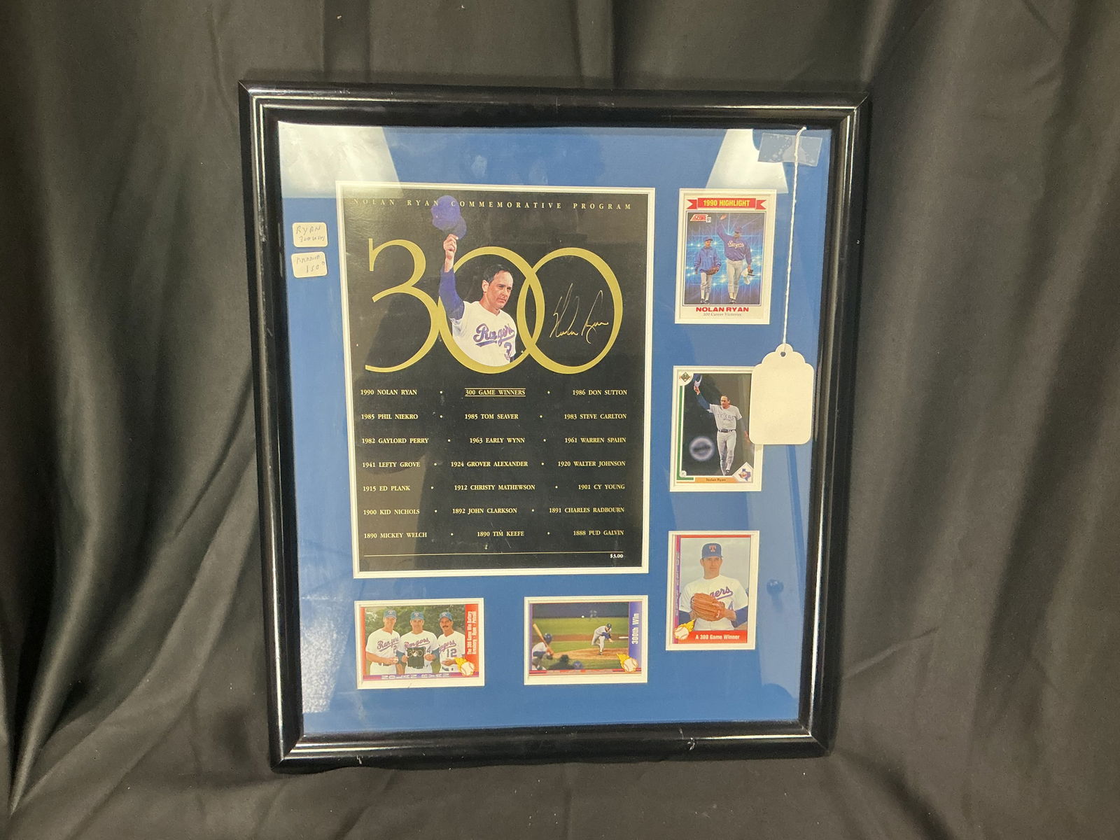 Nolan Ryan Autographed 300th Win Commemorative Framed Program with Cards Texas Rangers: Large gold-ink Nolan Ryan autograph on official 1990 300-win program, custom framed with five period cards, blue matting, black frame, approx 18x22 inches.