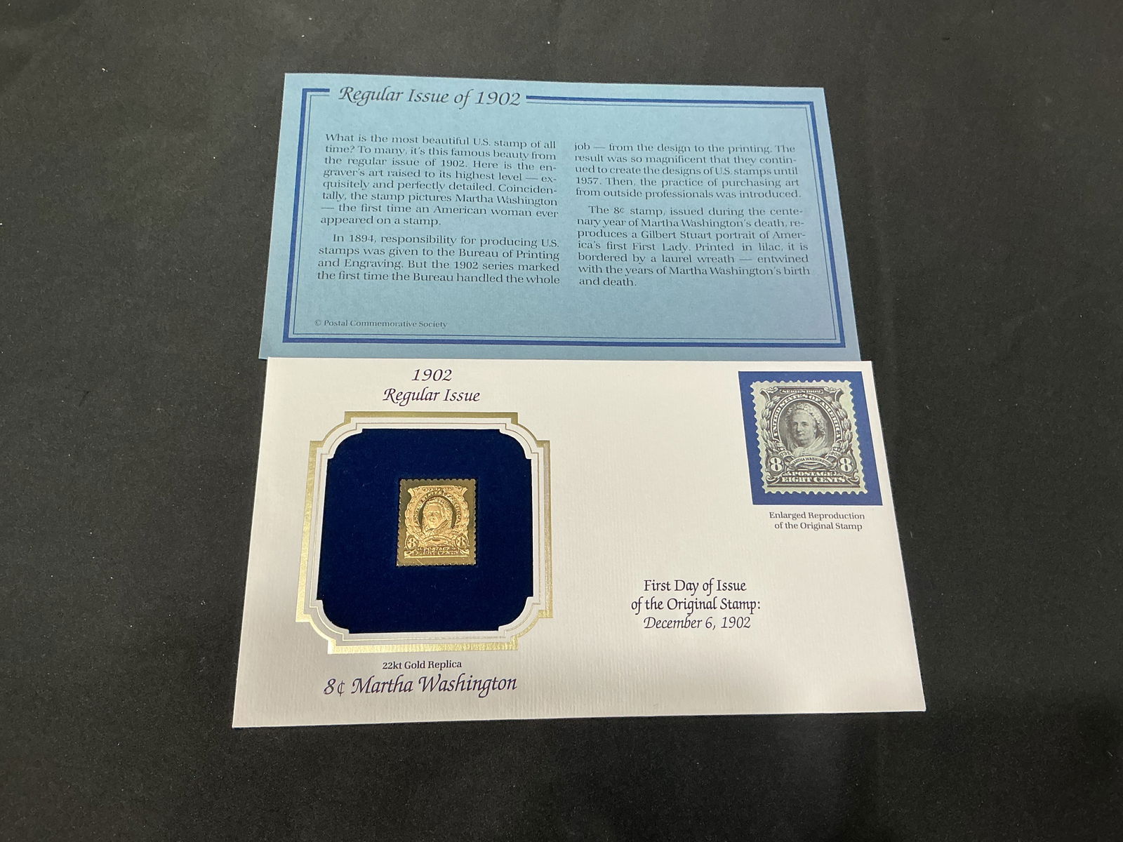 1902 8c Martha Washington 22kt Gold Replica Regular Issue: 22kt gold replica of the 8c Martha Washington from the 1902 regular issue, the first U.S. postage stamp to depict an American woman. Retained in the original blue velvet presentation card with the acc
