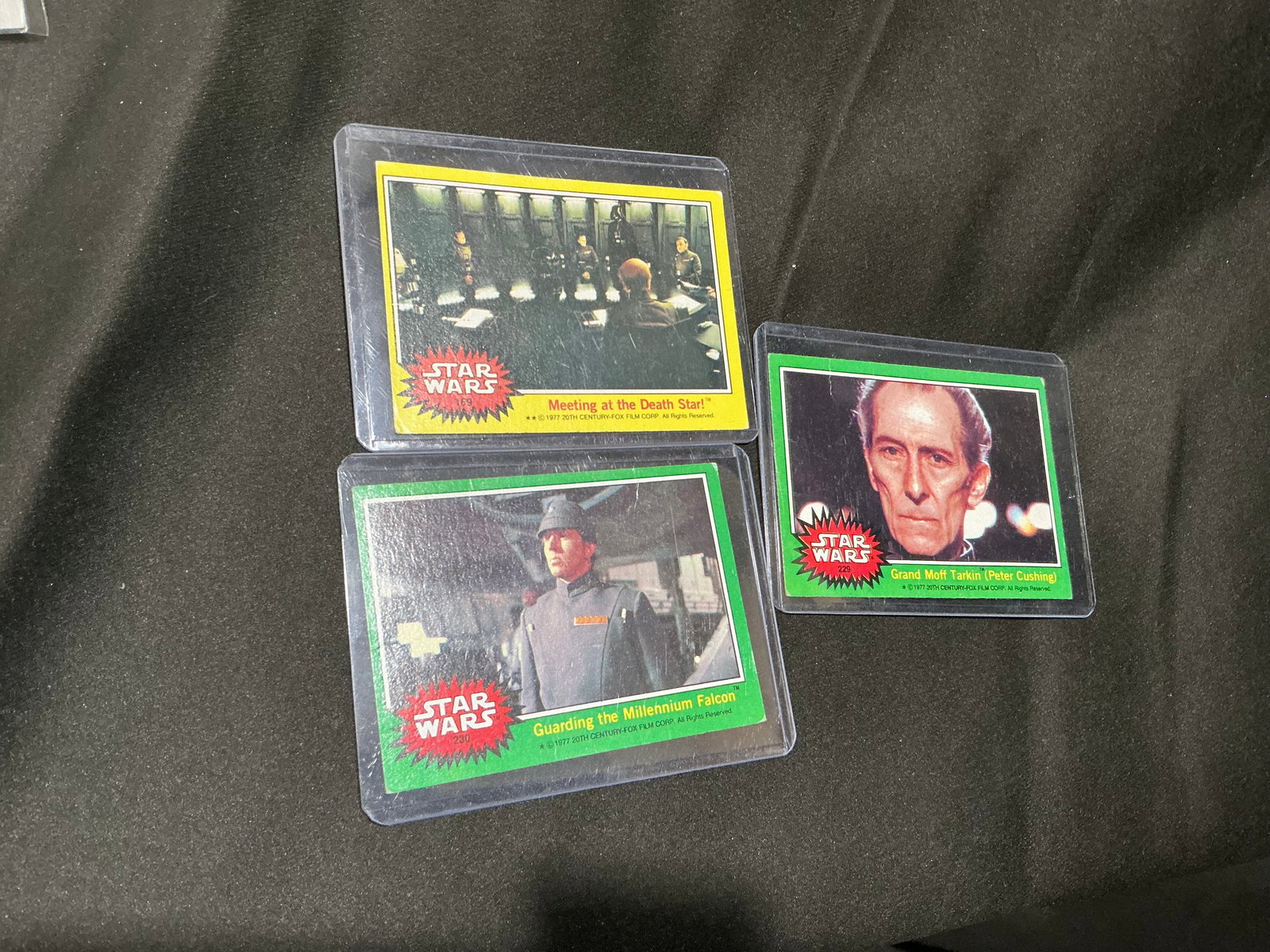Three vintage Star Wars trading cards (Millennium Falcon, Death Star, Grand Moff Tarkin): Three-card lot of vintage Star Wars trading cards including: 'Guarding the Millennium Falcon', 'Meeting at the Death Star', and 'Grand Moff Tarkin (Peter Cushing)'. Classic 1970s Topps-style Star