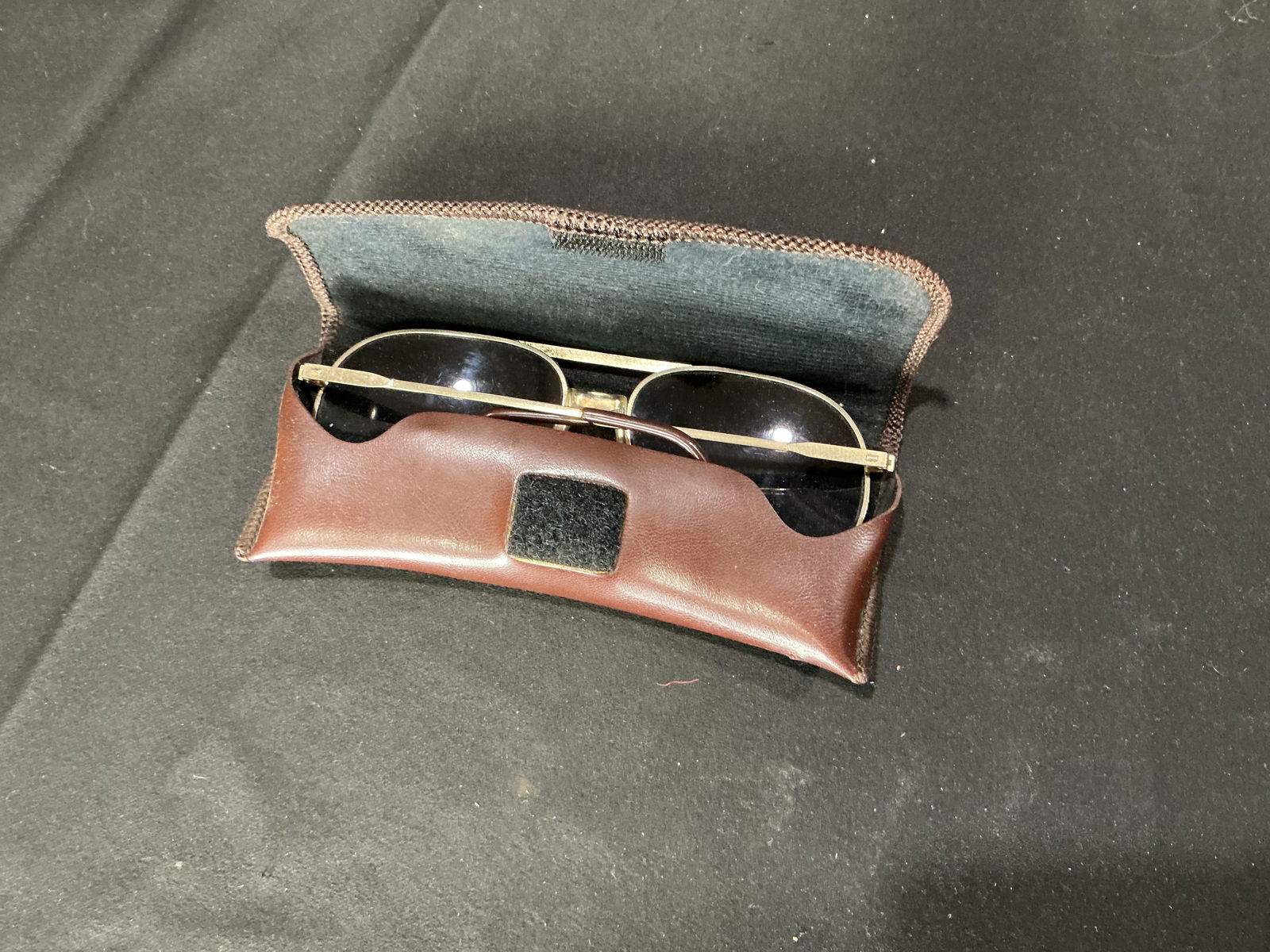 Vietnam era Vintage Gold-Tone Aviator Style Sunglasses with Case: Vintage aviator-style sunglasses featuring gold-tone metal frames with dark tinted lenses. Includes original brown leather snap-closure case. Classic mid-century aviator silhouette with thin wire arms