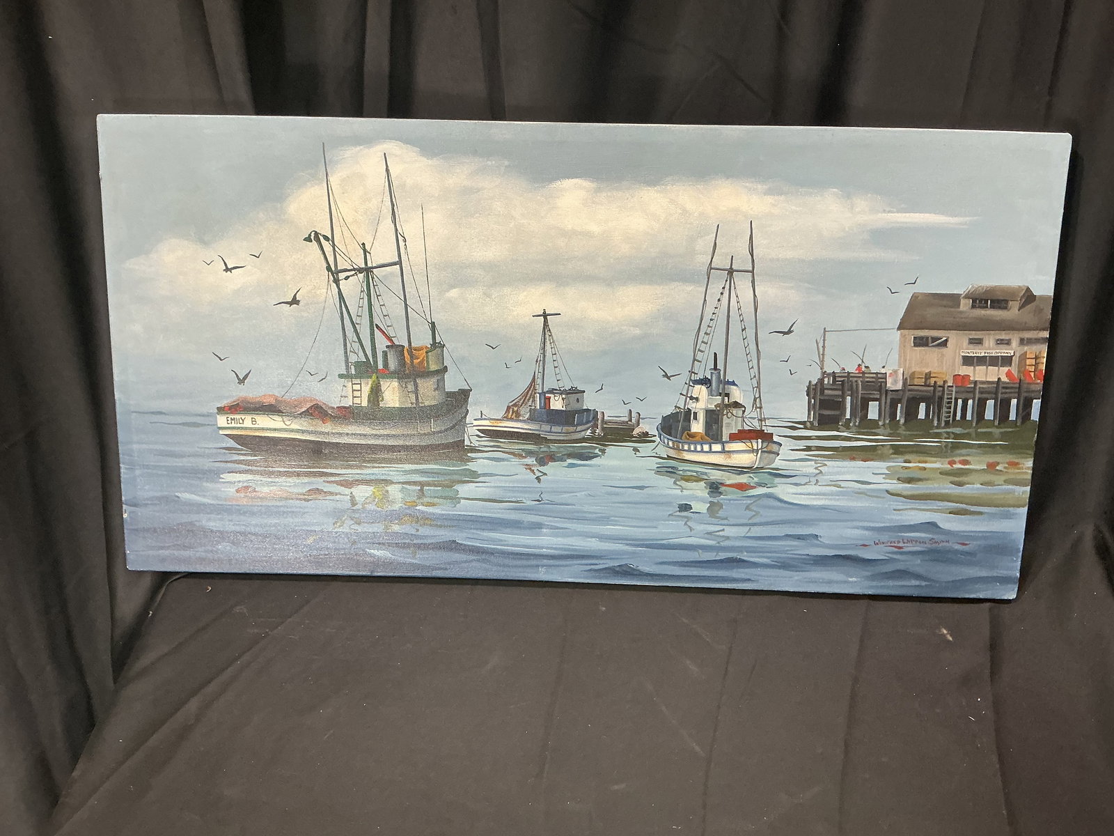 Signed Harbor Scene Painting by Winifred Witton Smith: Signed harbor scene painting depicting several working boats moored on calm water near a pier and waterfront structure, with seabirds in flight overhead. The composition is rendered in a realistic