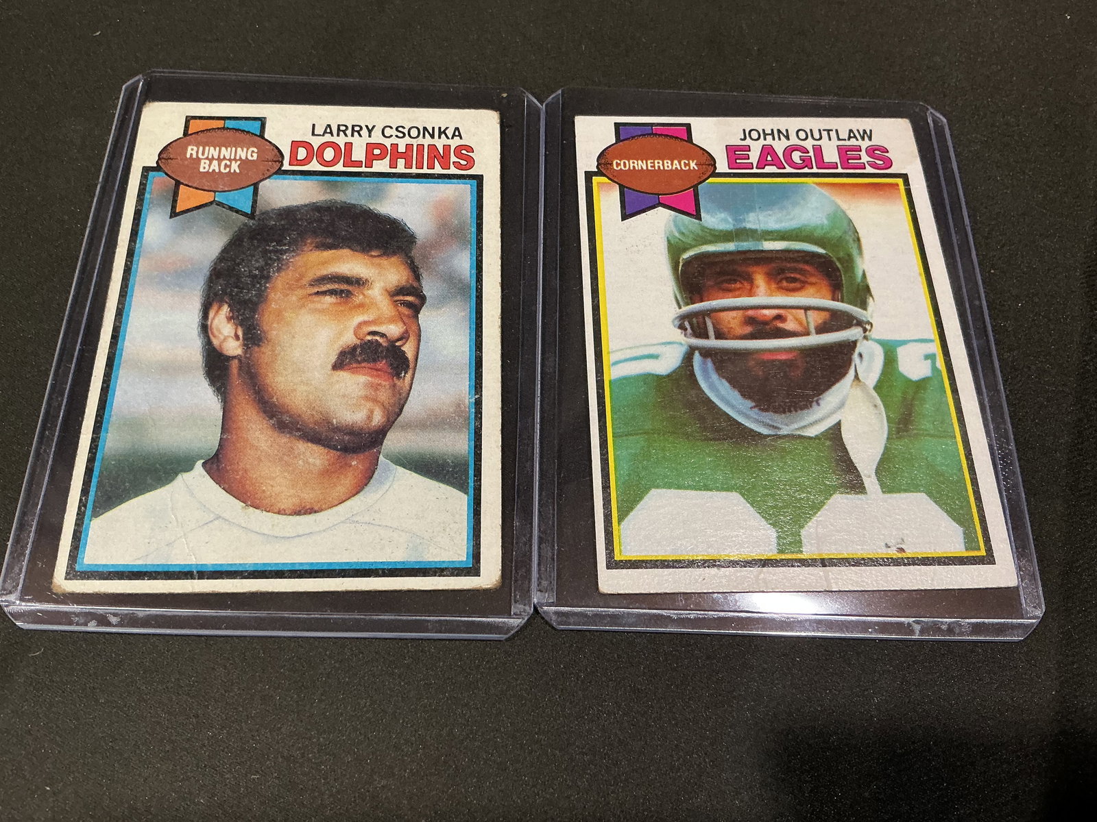 1979 Topps Larry Csonka and John Outlaw Football Cards (2): Pair of vintage 1979 Topps football cards featuring Larry Csonka of the Miami Dolphins and John Outlaw of the Philadelphia Eagles. Classic late-1970s Topps design with full statistical backs and biogr
