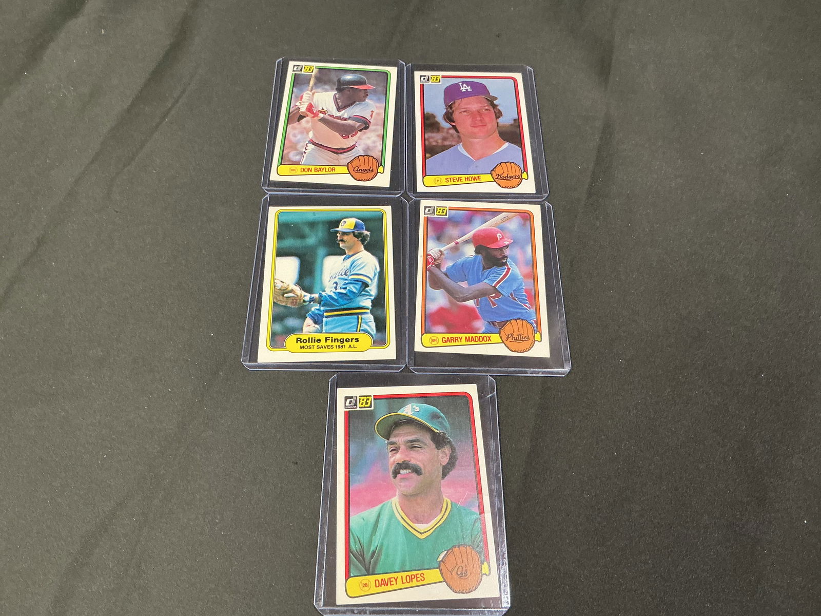 1983 Donruss Baseball Card Group Including Don Baylor and Davey Lopes (5): Group of five 1983 Donruss baseball cards including Don Baylor, Steve Howe, Garry Maddox, Davey Lopes, and a Fleer Rollie Fingers card. Features classic early-1980s card designs with full statistical
