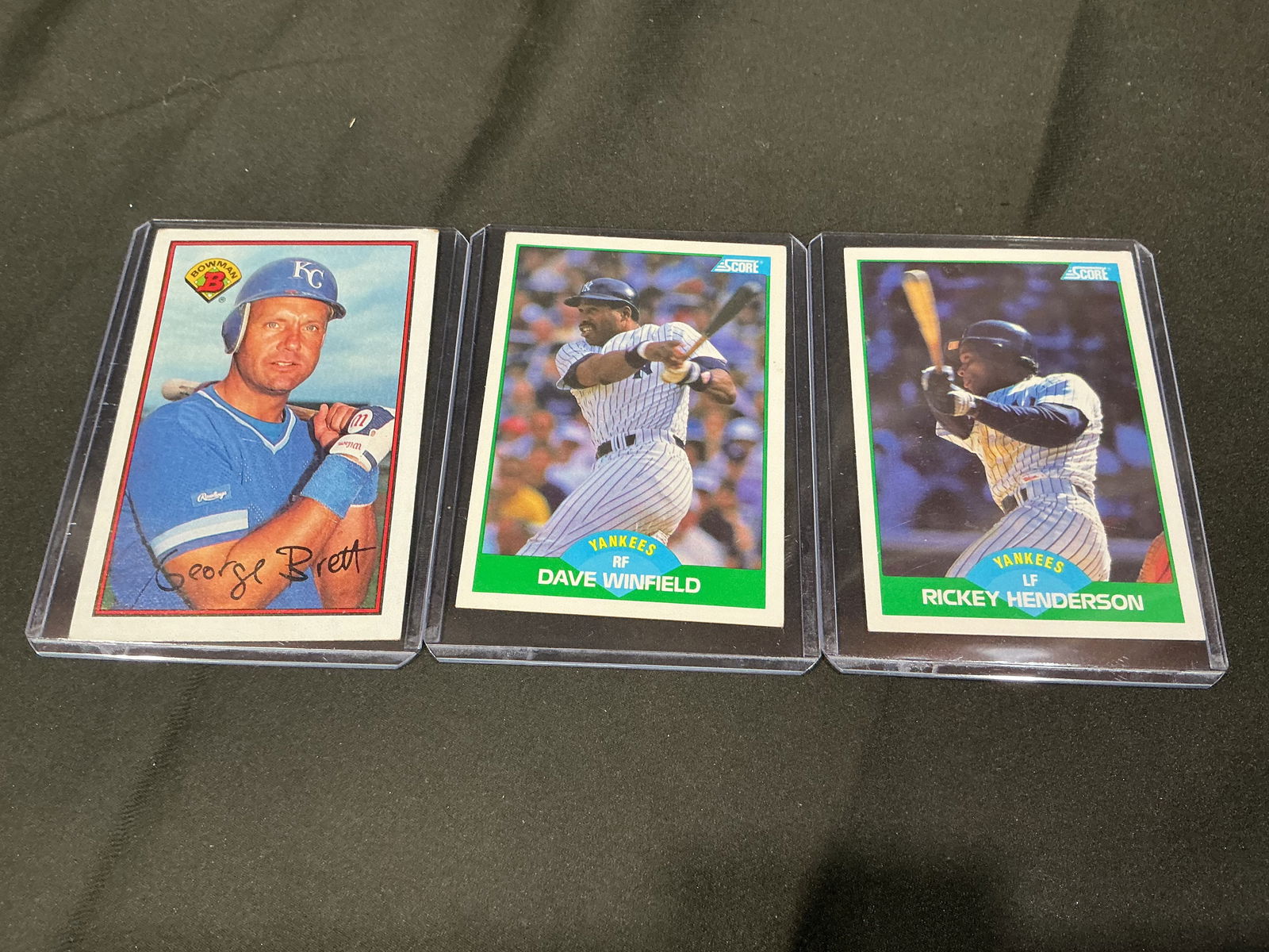 Baseball Card Group Including George Brett, Dave Winfield and Rickey Henderson (3): Group of three baseball cards featuring Hall of Fame caliber players including George Brett (Kansas City Royals), Dave Winfield (New York Yankees), and Rickey Henderson (New York Yankees). Includes Bo