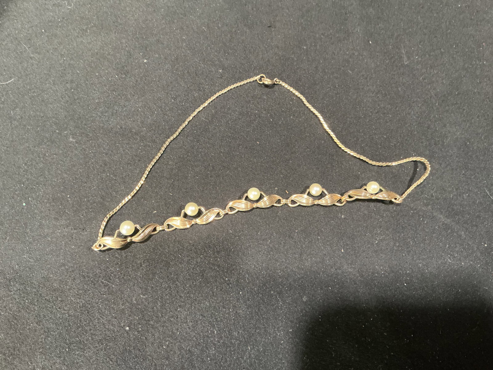 Vintage Gold Tone Faux Pearl Link Necklace: Vintage gold tone necklace featuring a decorative front section with twisted ribbon style links accented by round faux pearls. Elegant mid century design with fine chain and clasp closure.